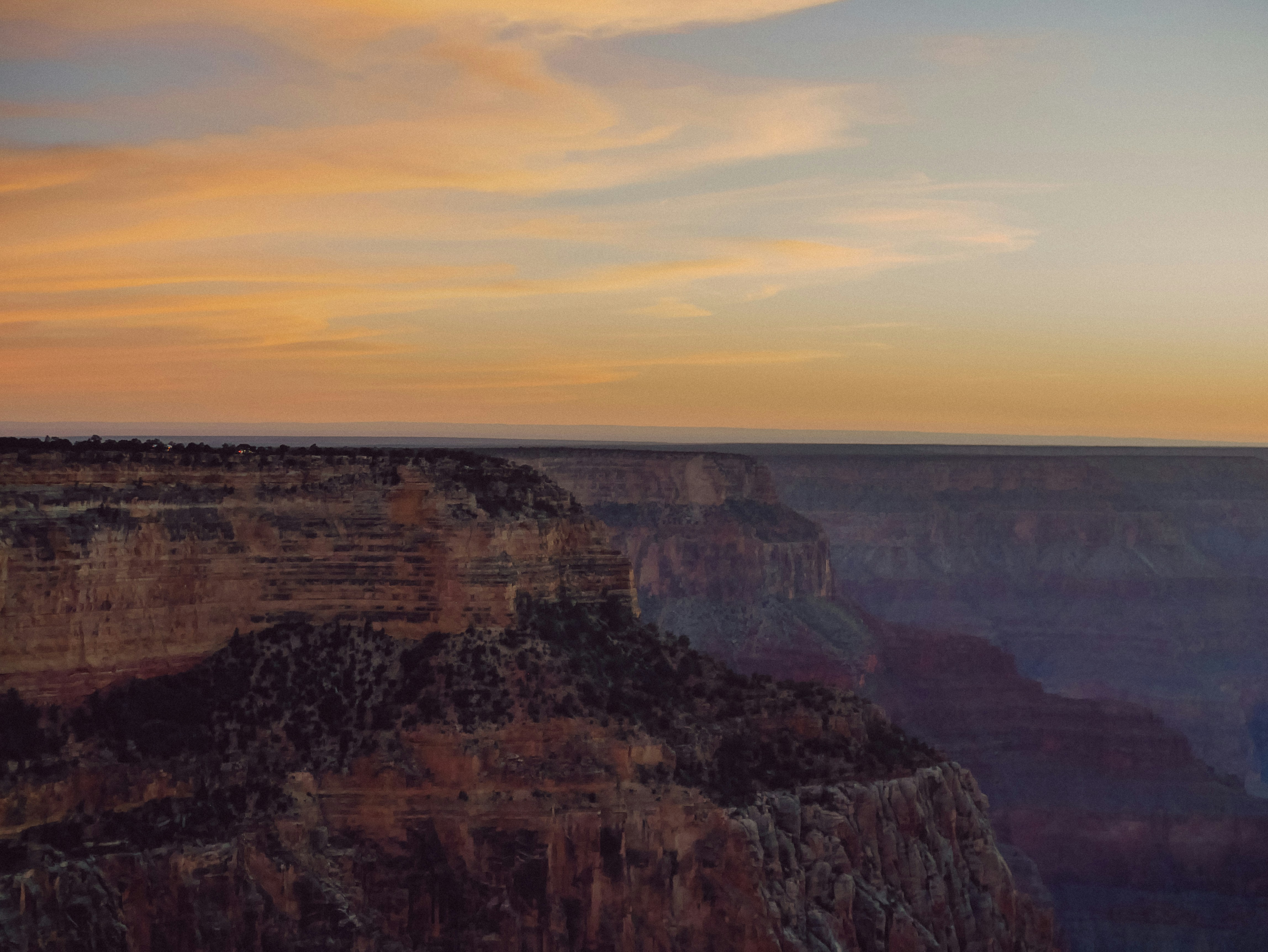 A vast canyon landscape under a colorful sunset sky.