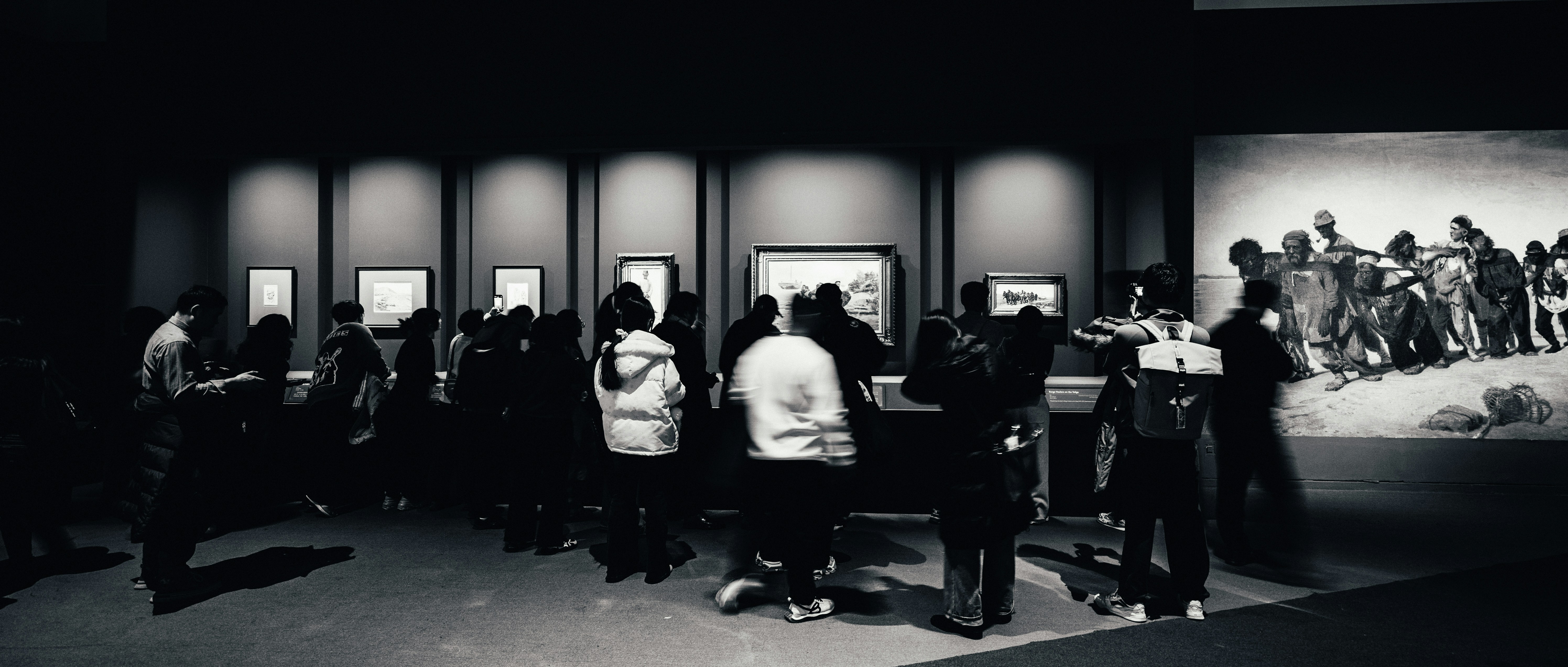 People viewing exhibits in a dimly lit museum gallery
