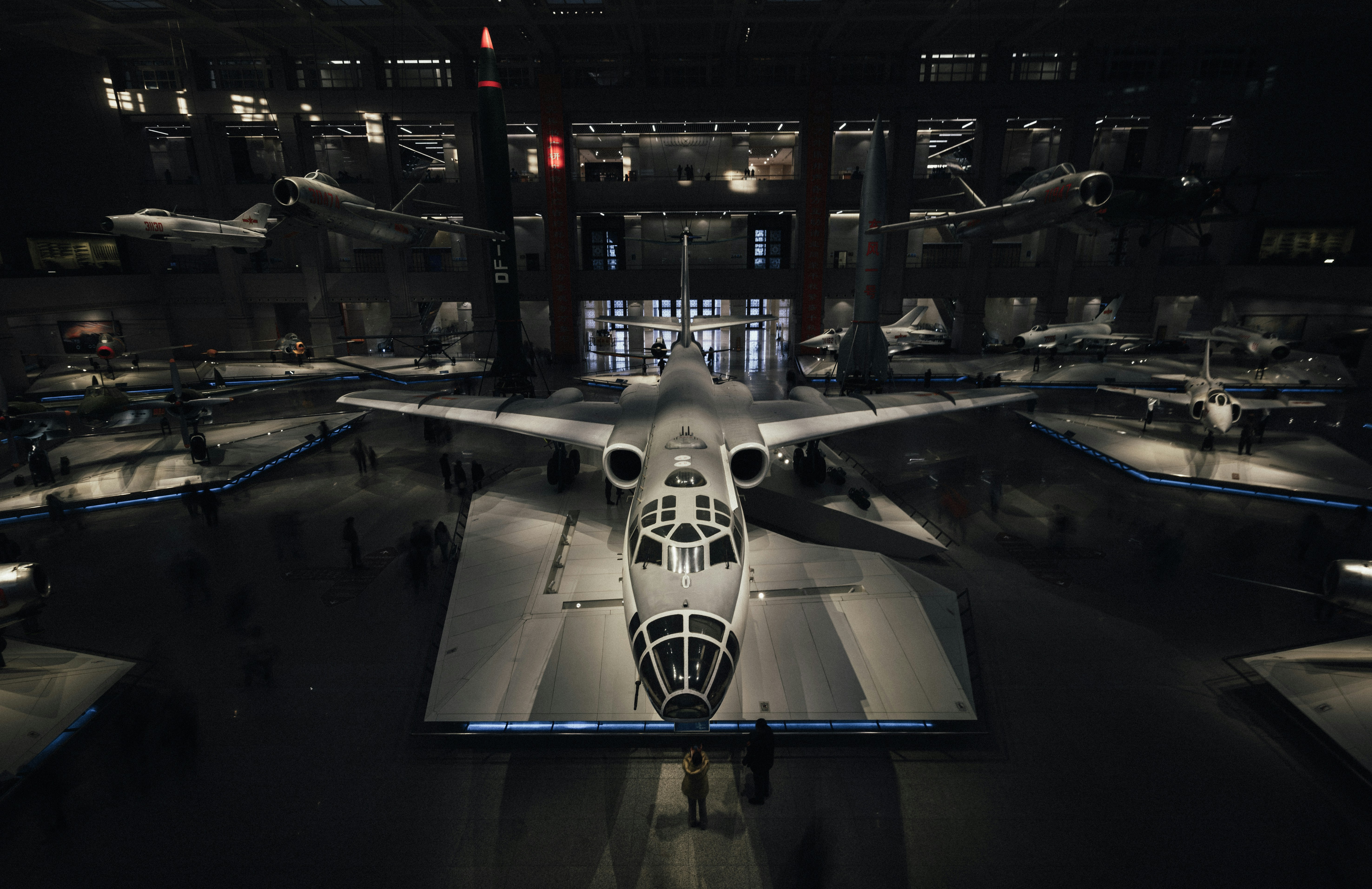 Futuristic white aircraft on display inside a dimly lit museum.