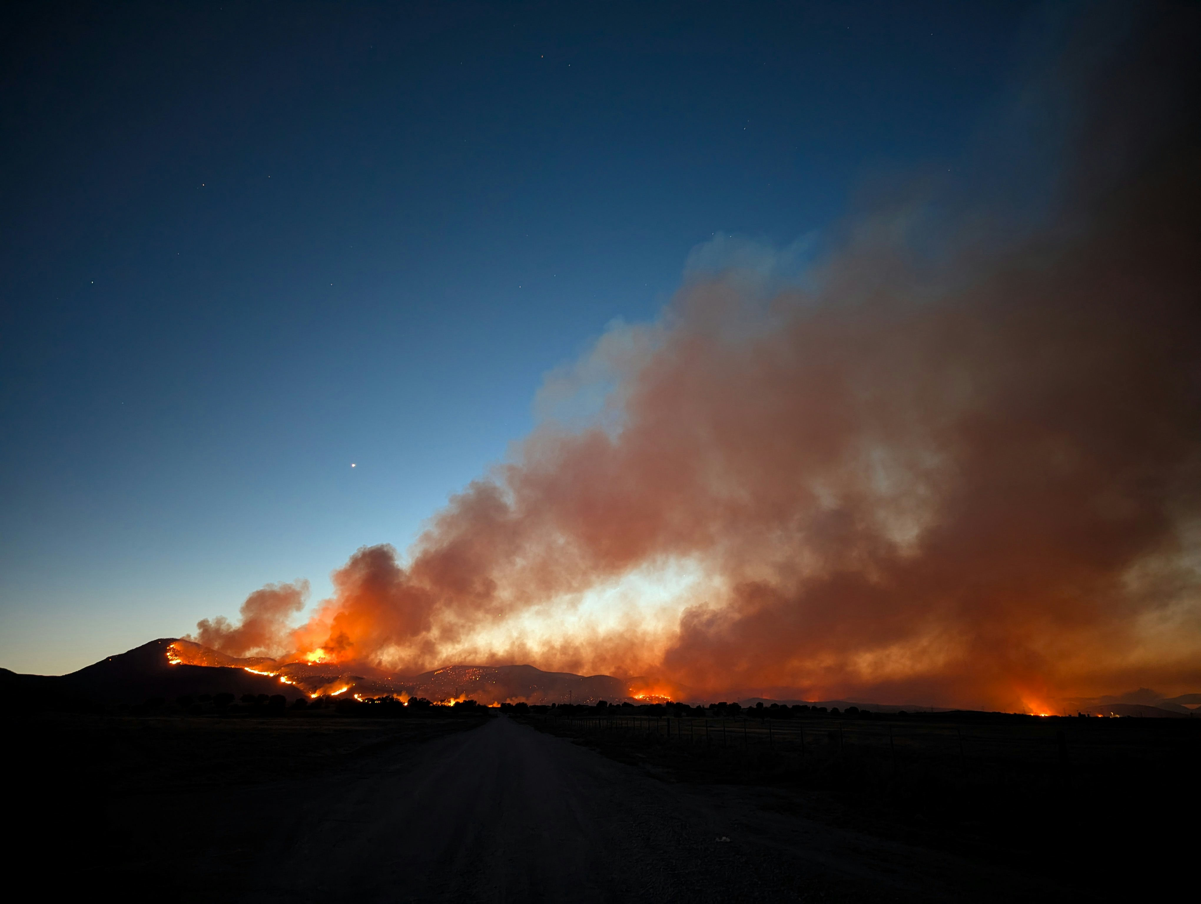 Wildfire burning across a dark landscape at night.