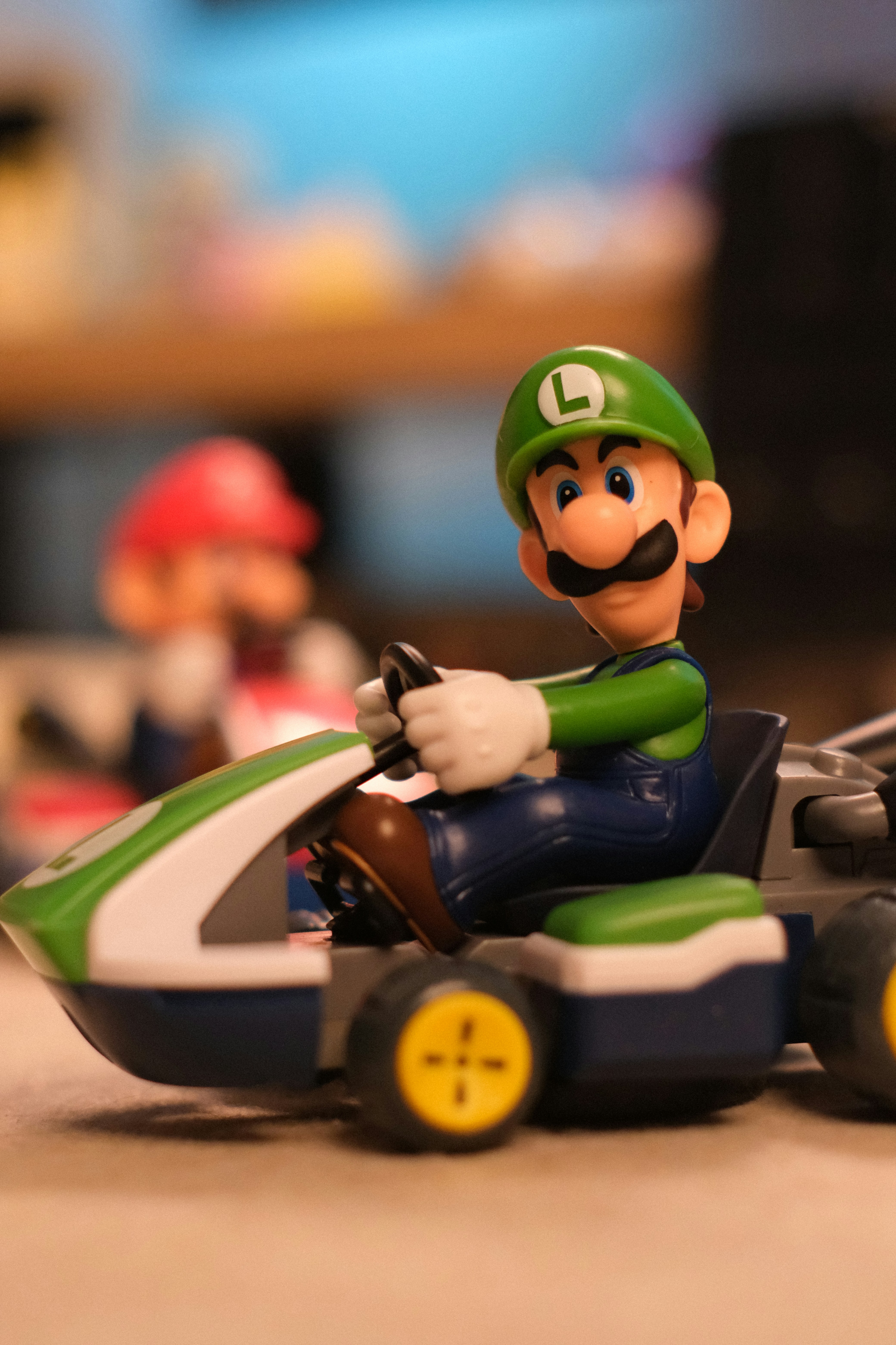 Luigi in a go-kart with mario blurred in the background.