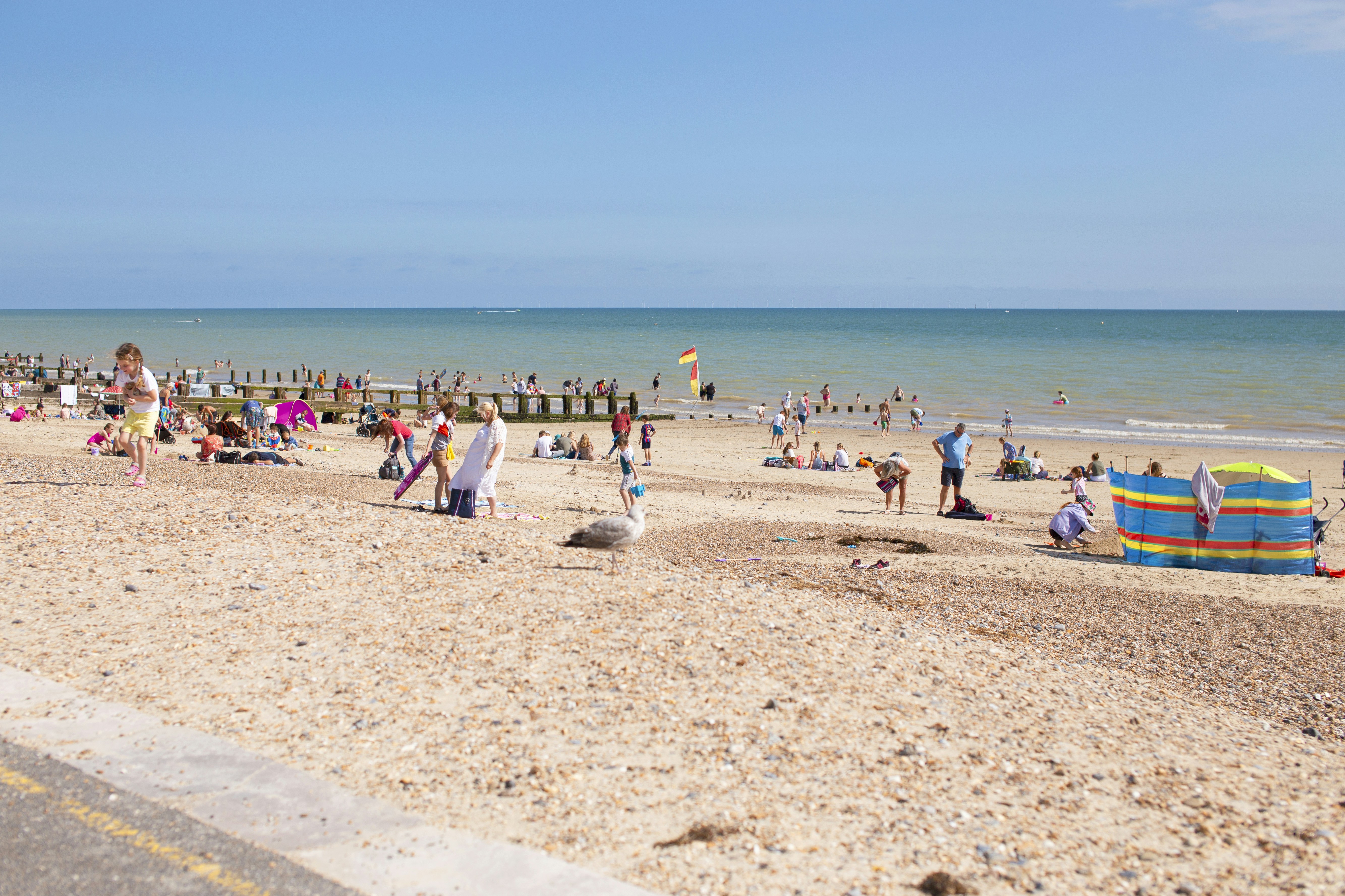 Sunny beach with people enjoying the ocean.