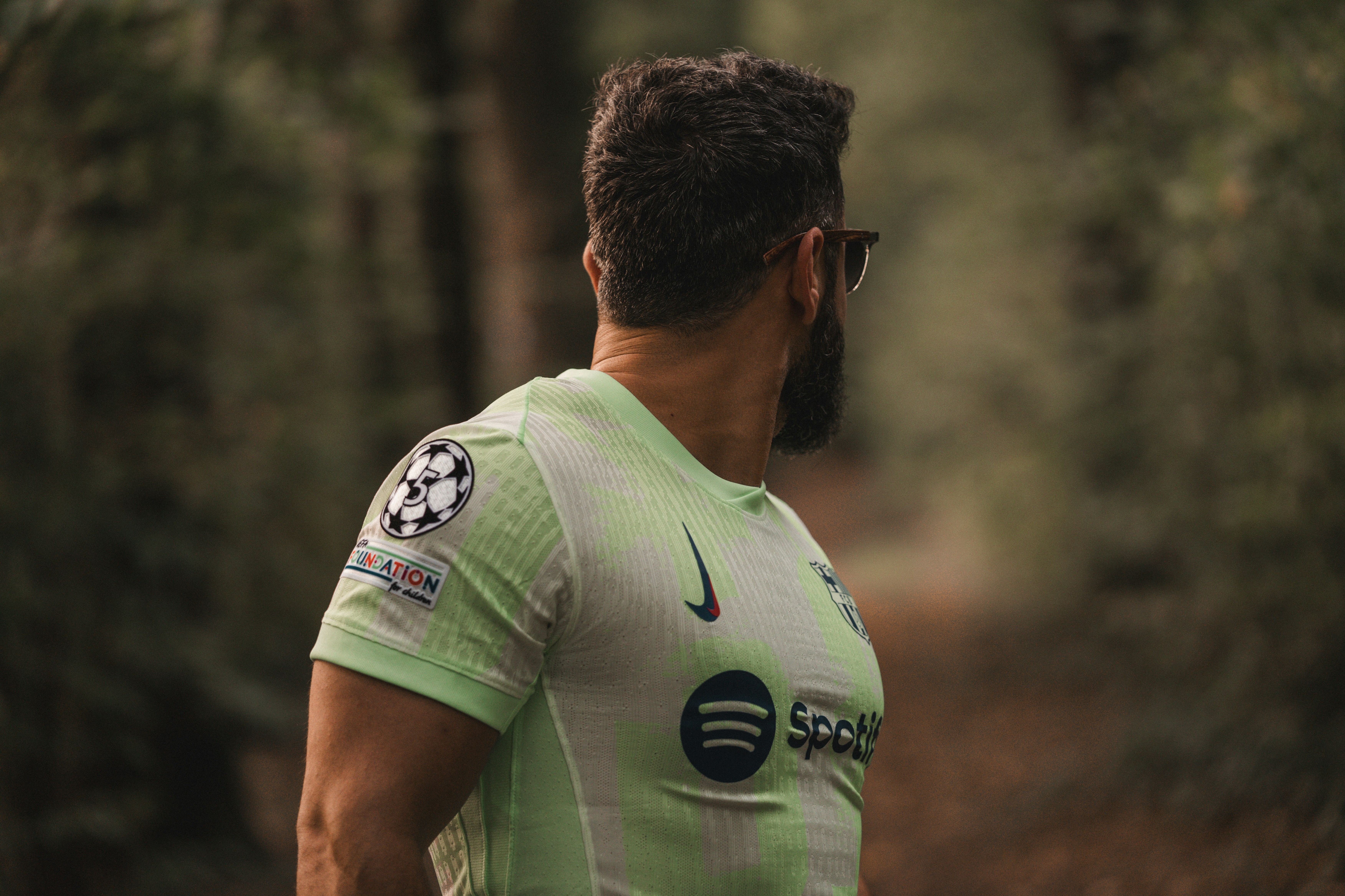 Uomo con una maglia verde chiaro che guarda in una foresta.
