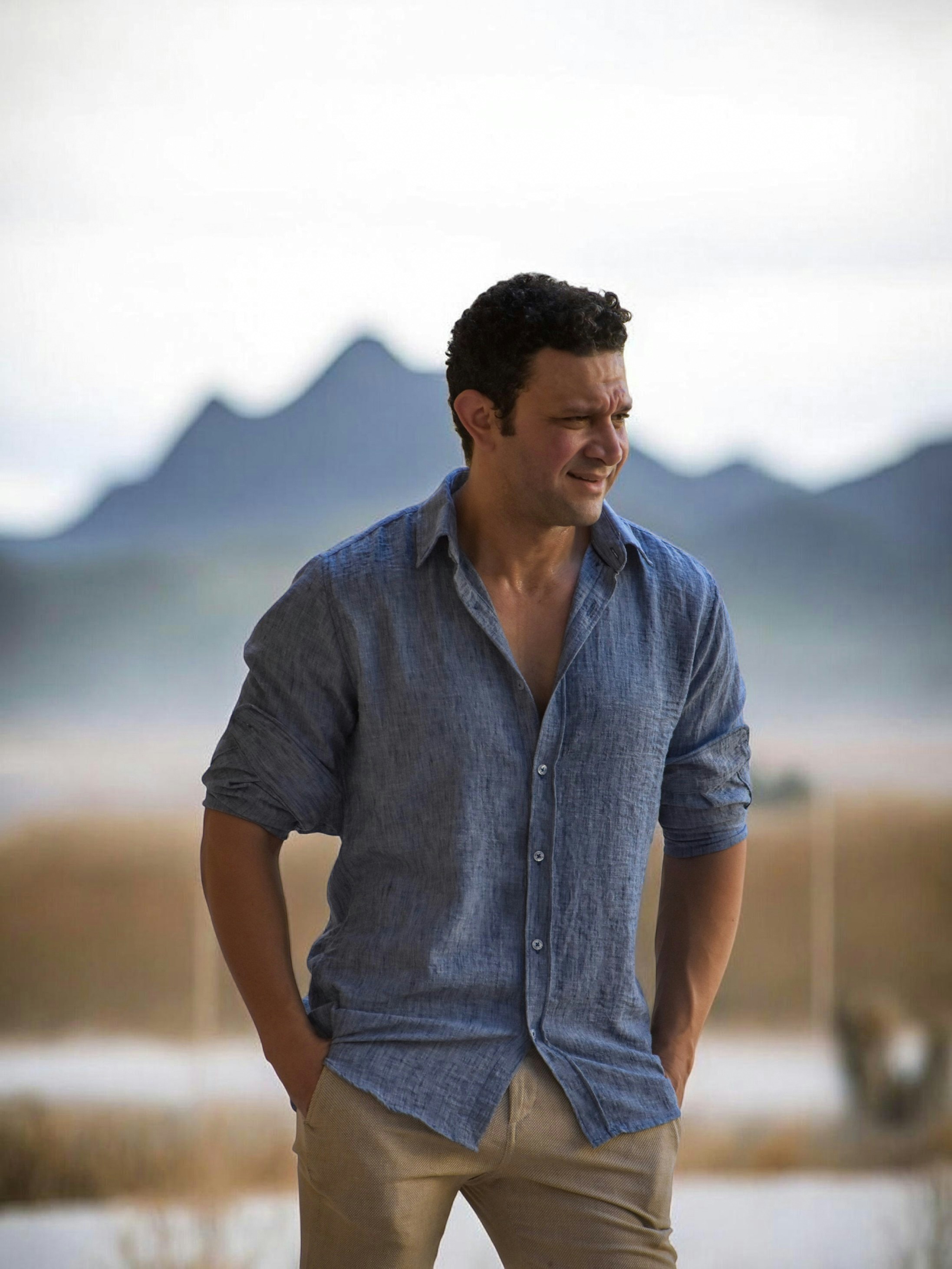 Man in a chambray linen shirt in front of mountains