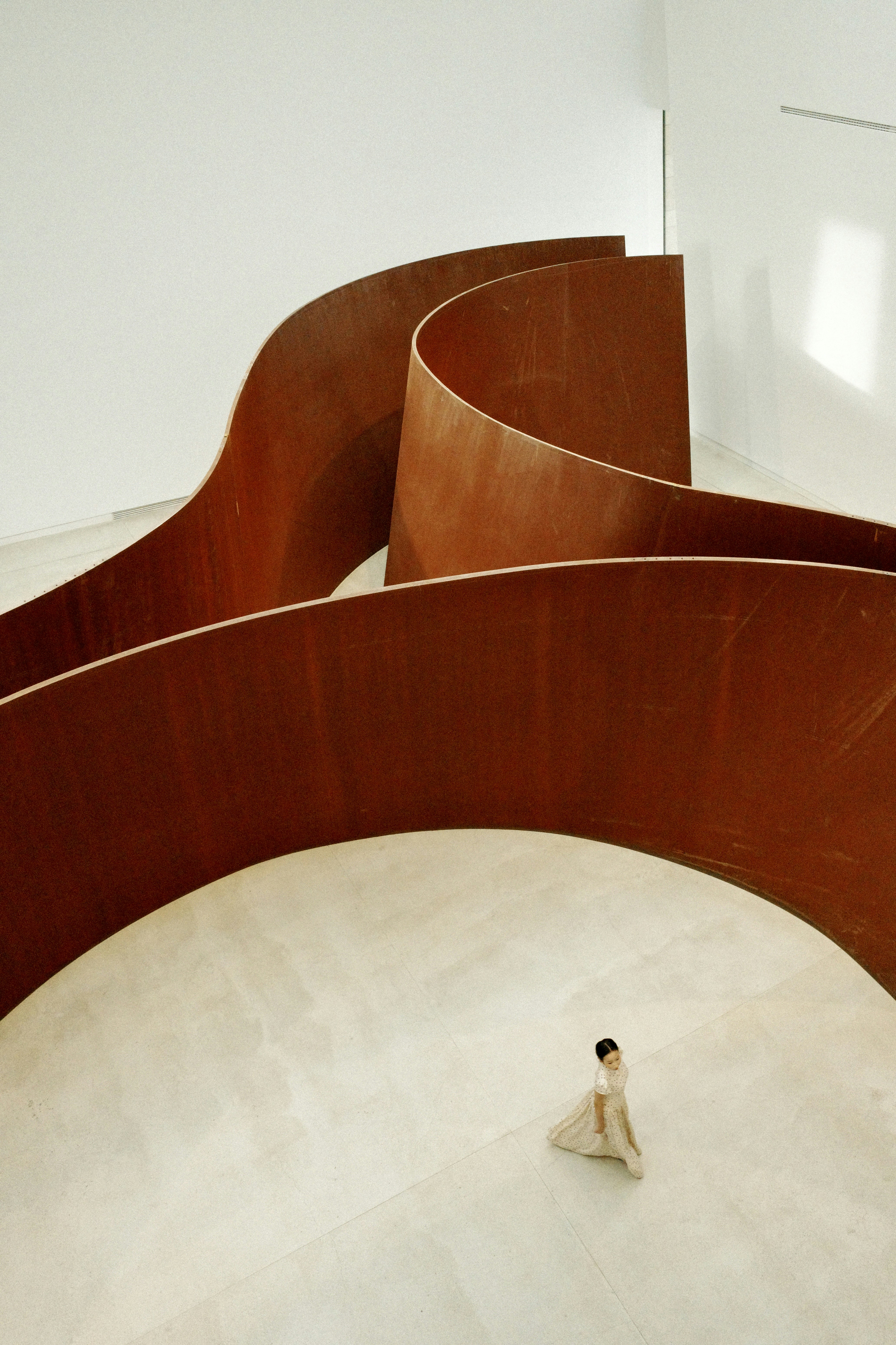 Person walking among large rusty metal sculptures.