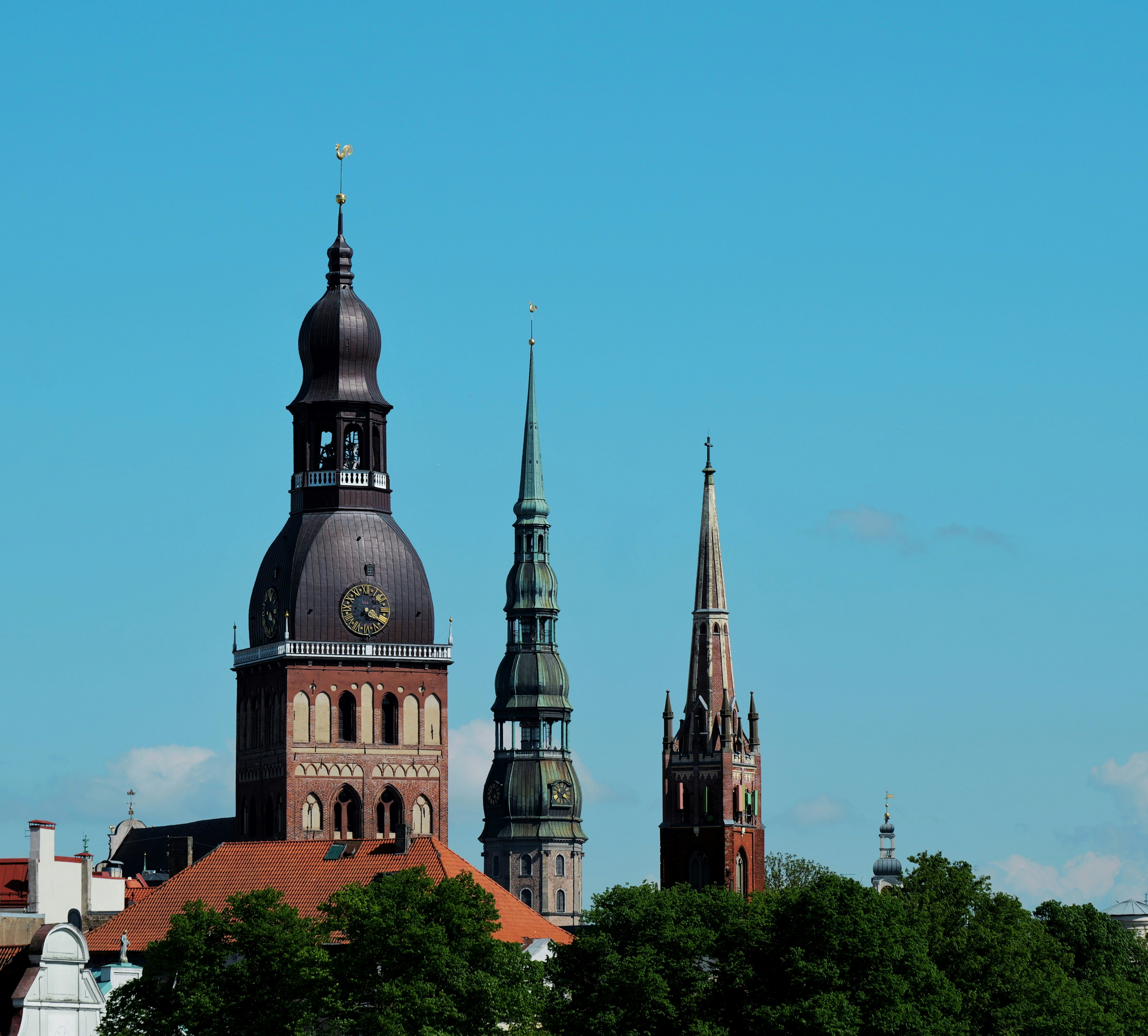Three historic church spires rise against a clear blue sky.