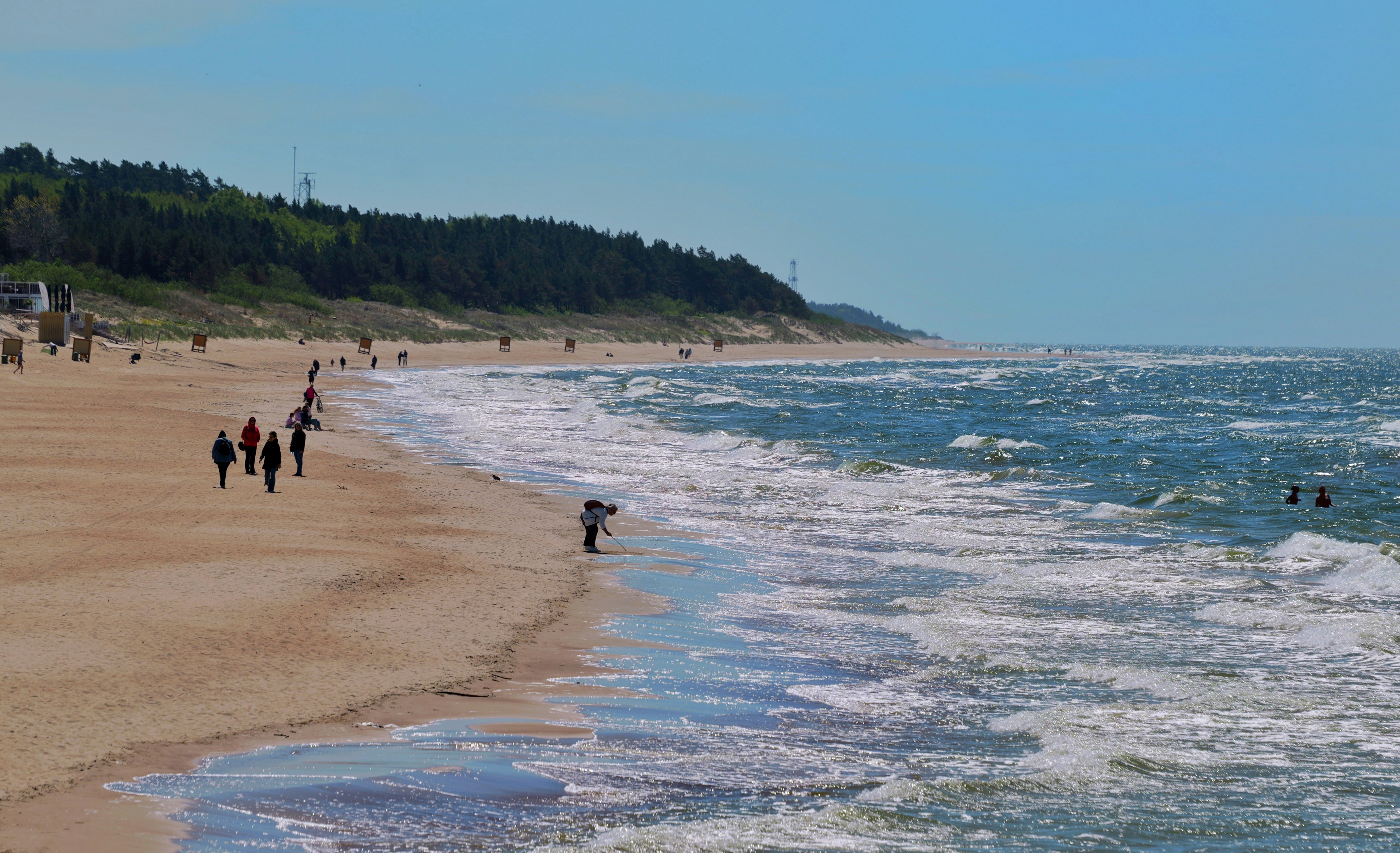 People walk on a sandy beach with ocean waves.