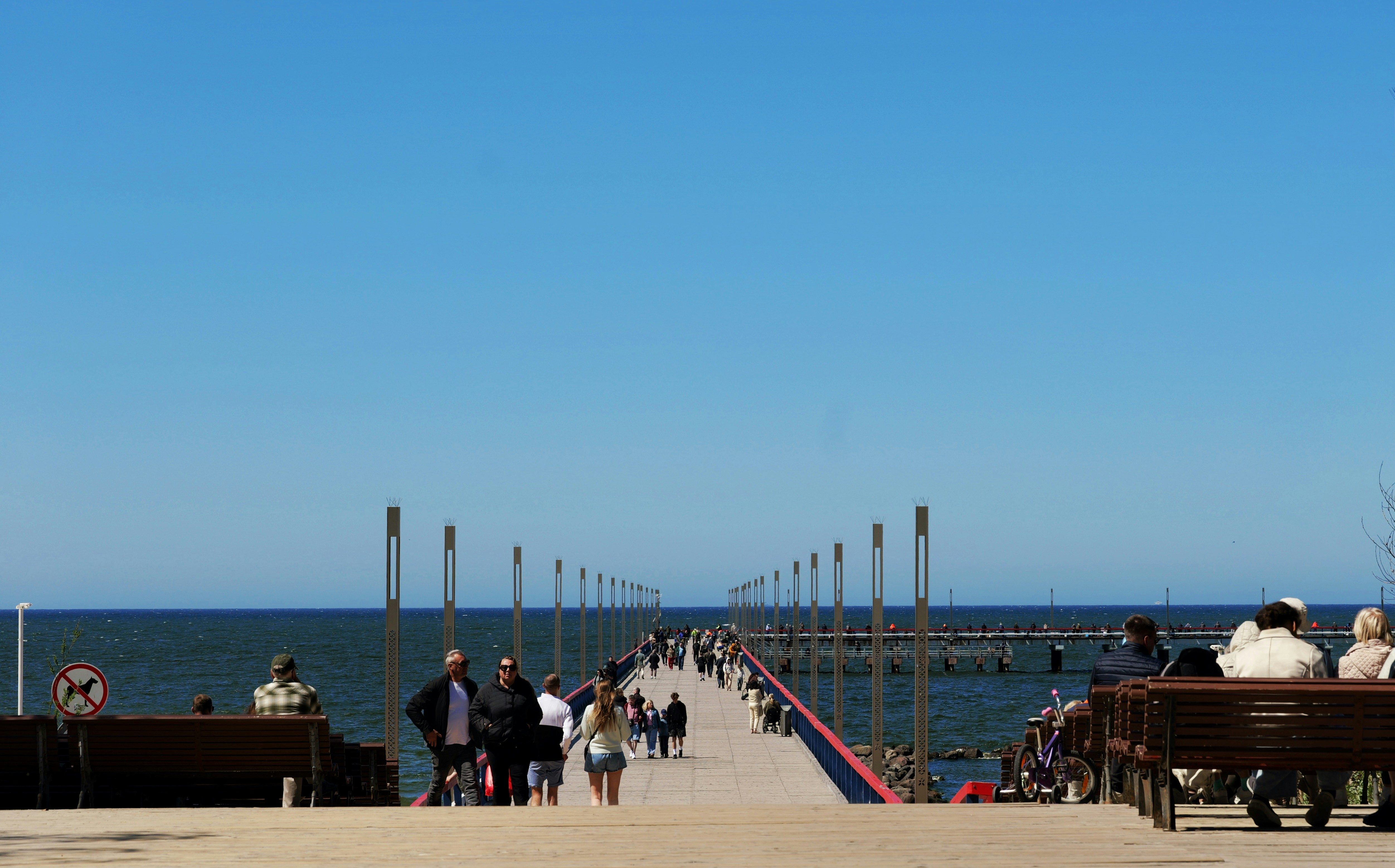 A long pier with people extends into the ocean.