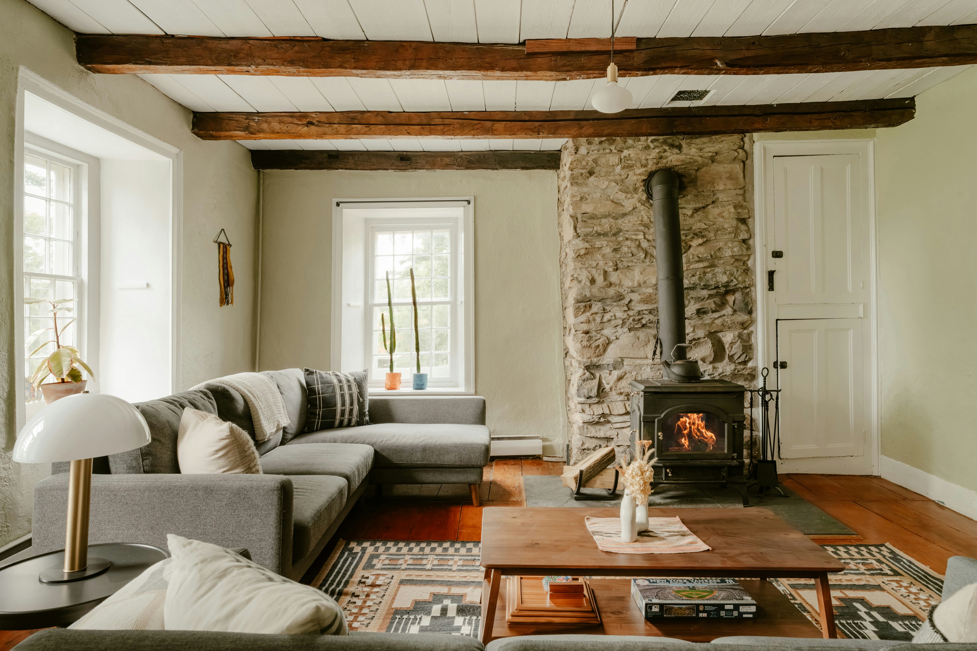 Cozy living room with lit wood stove and gray sectional