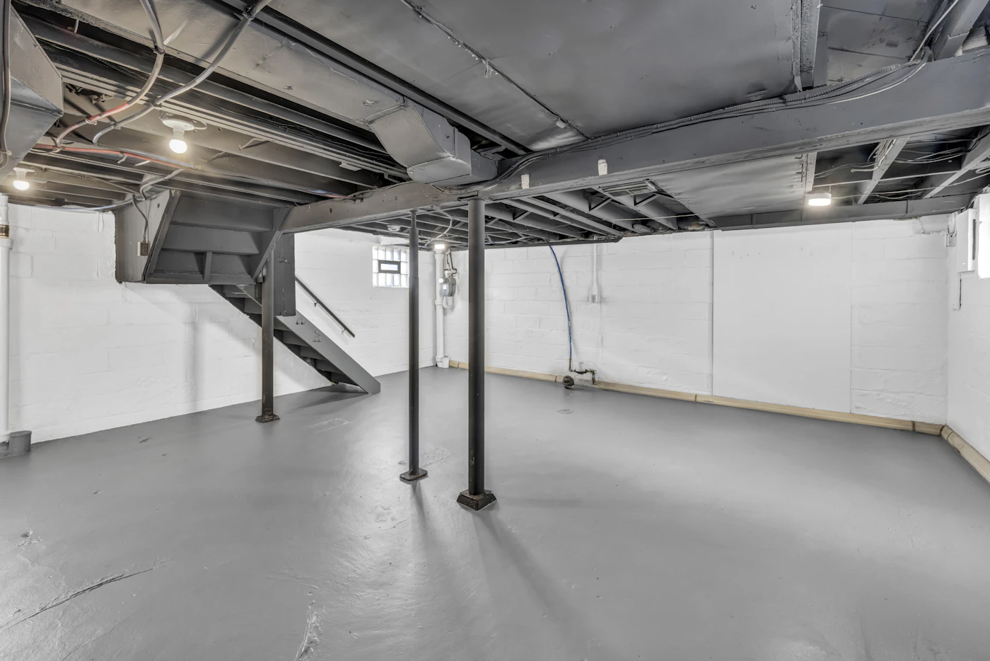Unfinished basement with exposed joists and support columns
