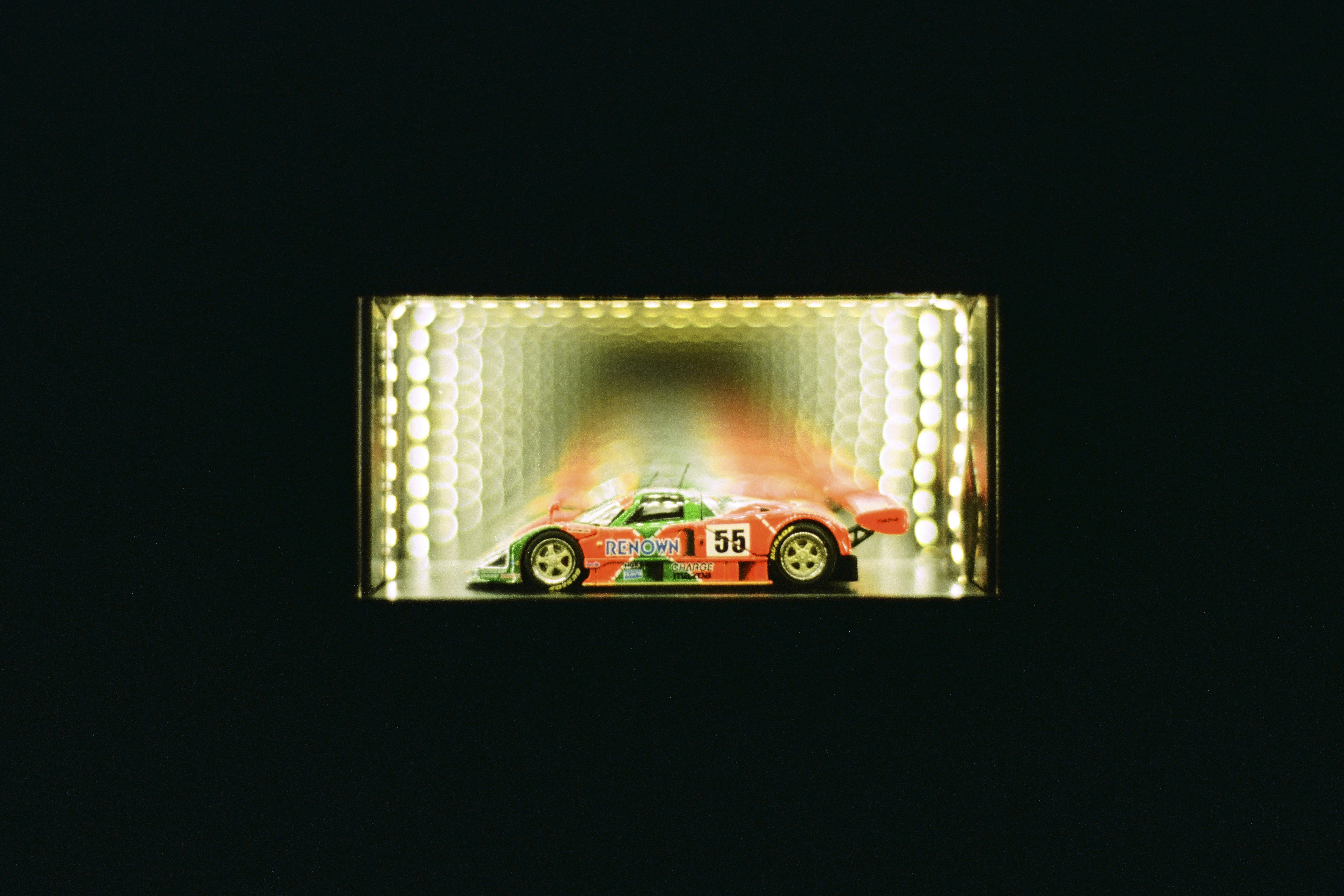 Modello di auto da corsa rosso e verde in un tunnel illuminato.