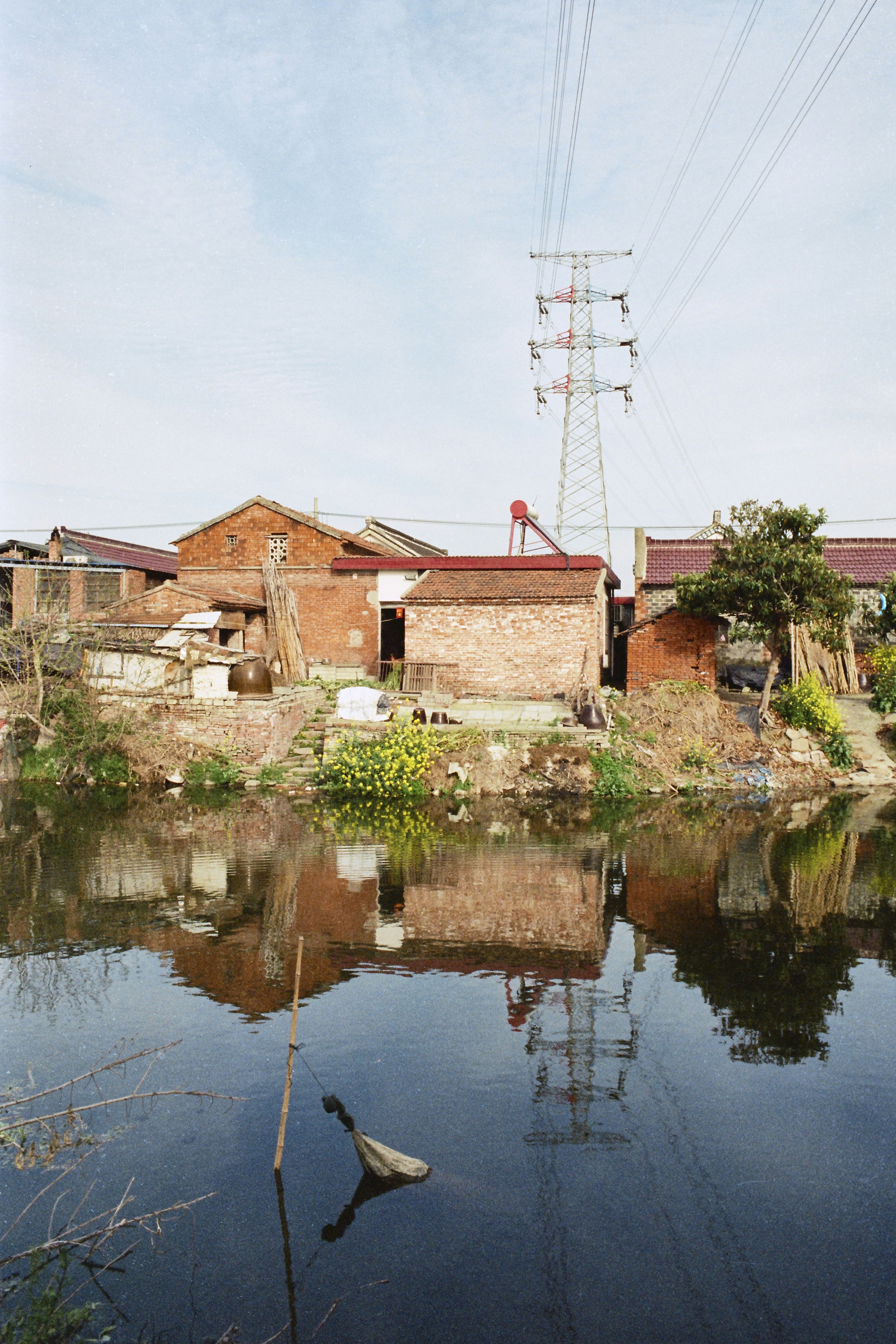 Case in mattoni e una torre elettrica riflessa nell'acqua calma.
