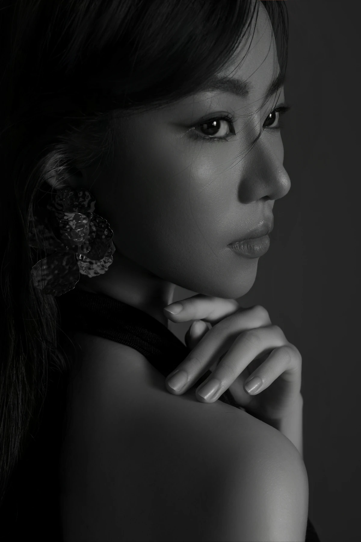 Retrato en blanco y negro de una mujer con la mano bajo el mentón y el pómulo iluminado