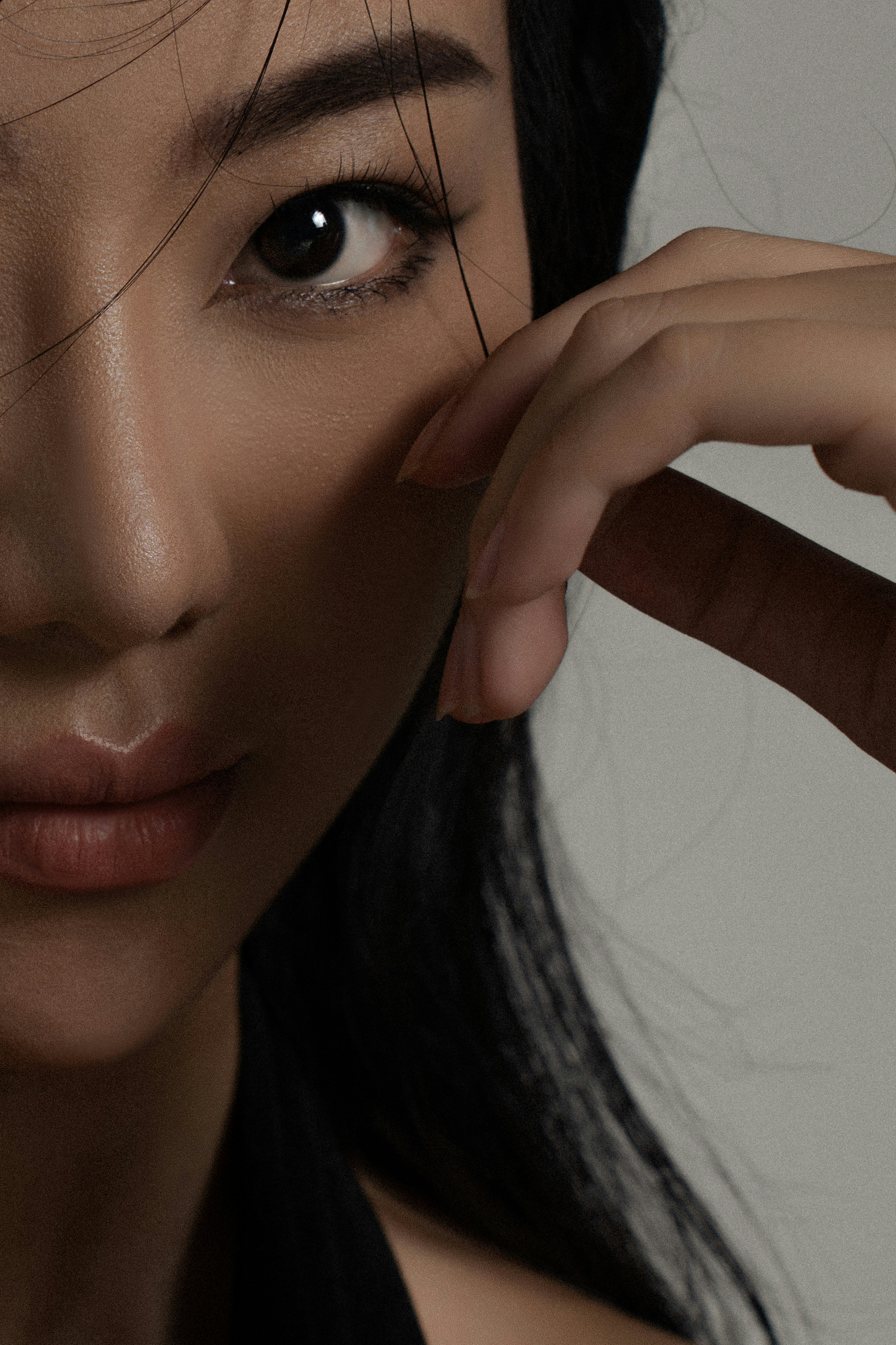 女性の顔と手が明るい背景に映っています。