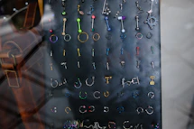 Many colorful body piercings and earrings on a dark display