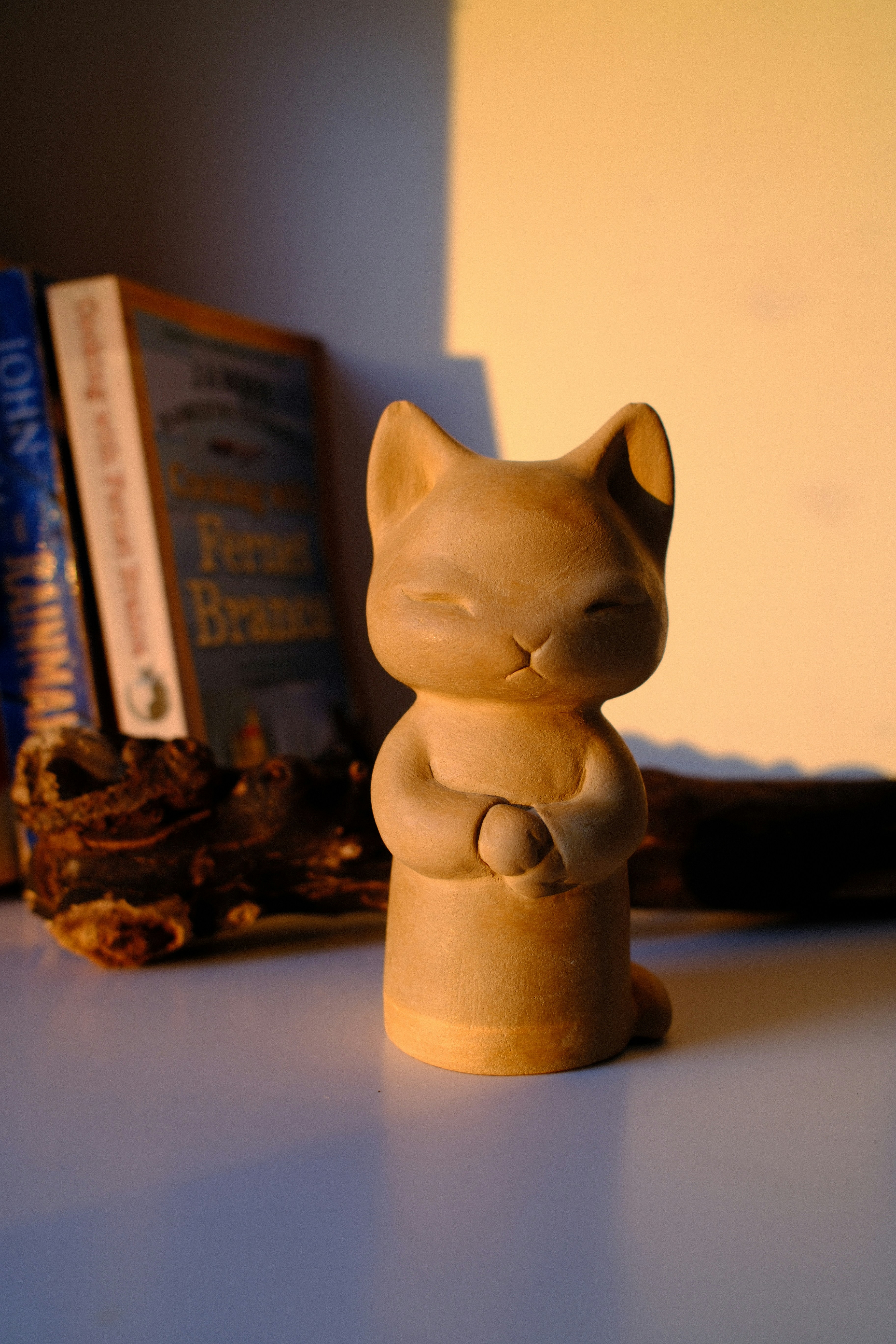 A peaceful cat figurine illuminated by warm golden light.