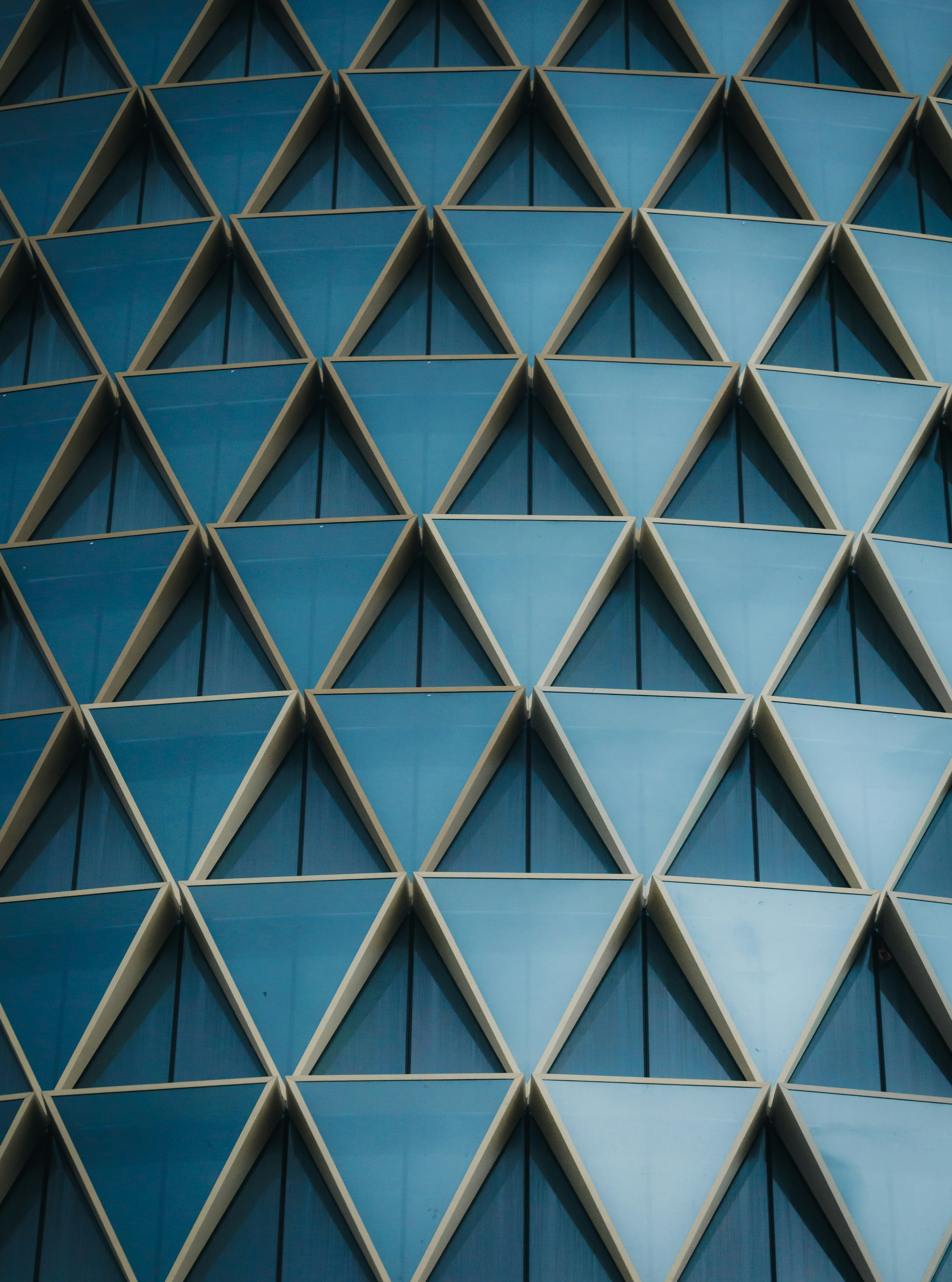 Geometric blue triangular windows on a modern building facade.