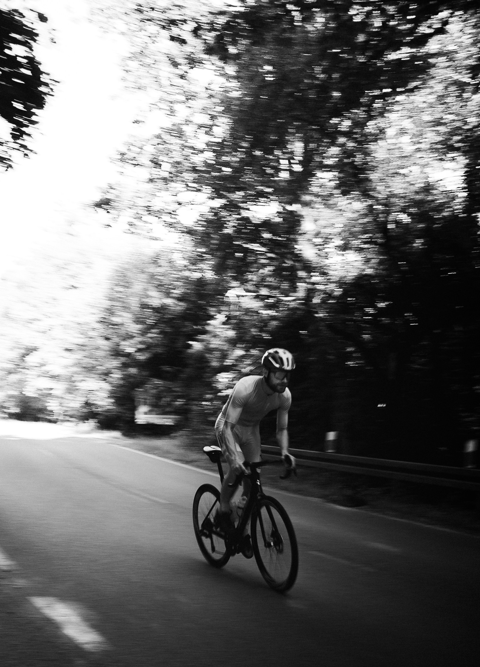 Black and white cyclist rides a road bike outdoors.