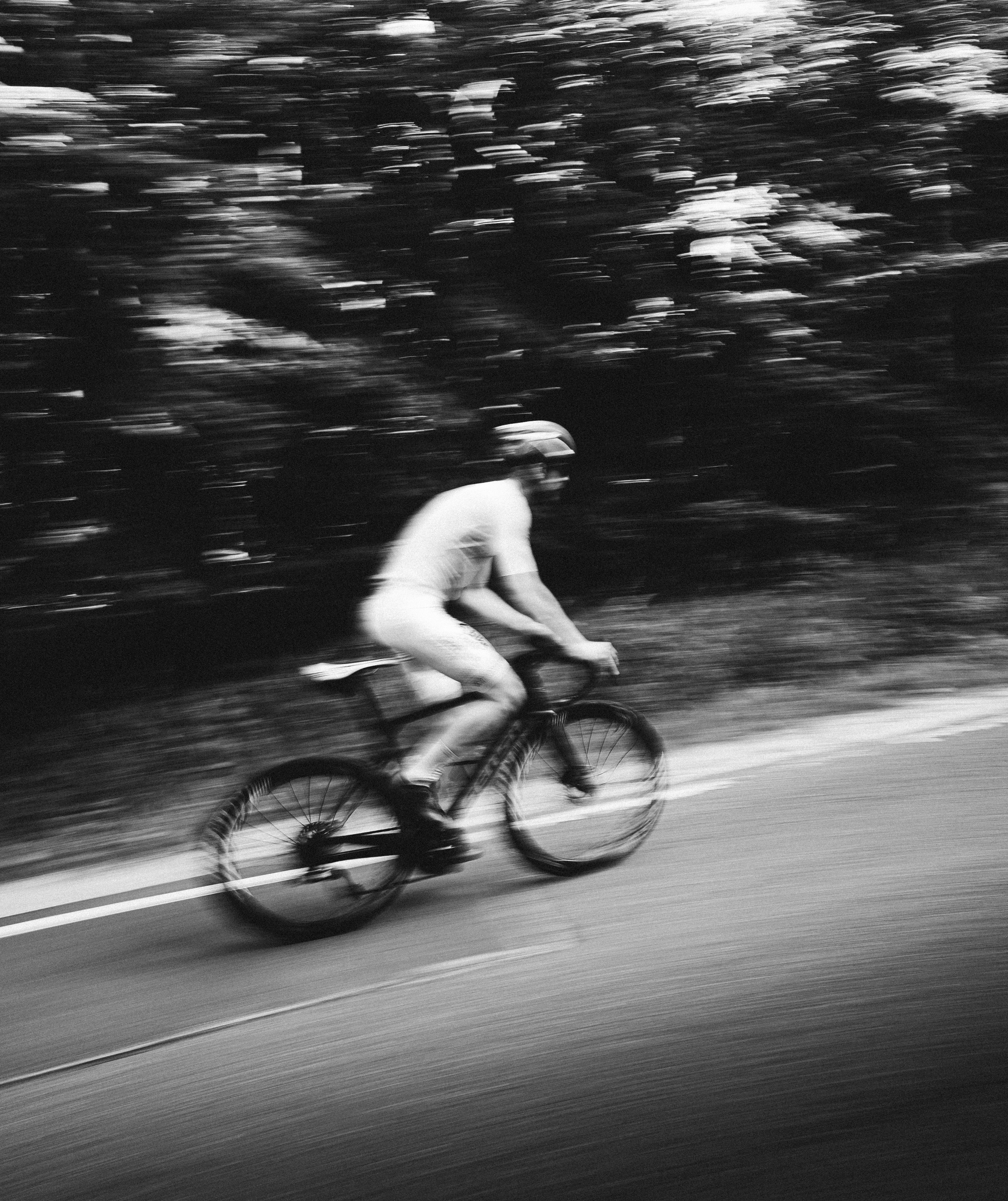 Black and white cyclist in motion blur on road.