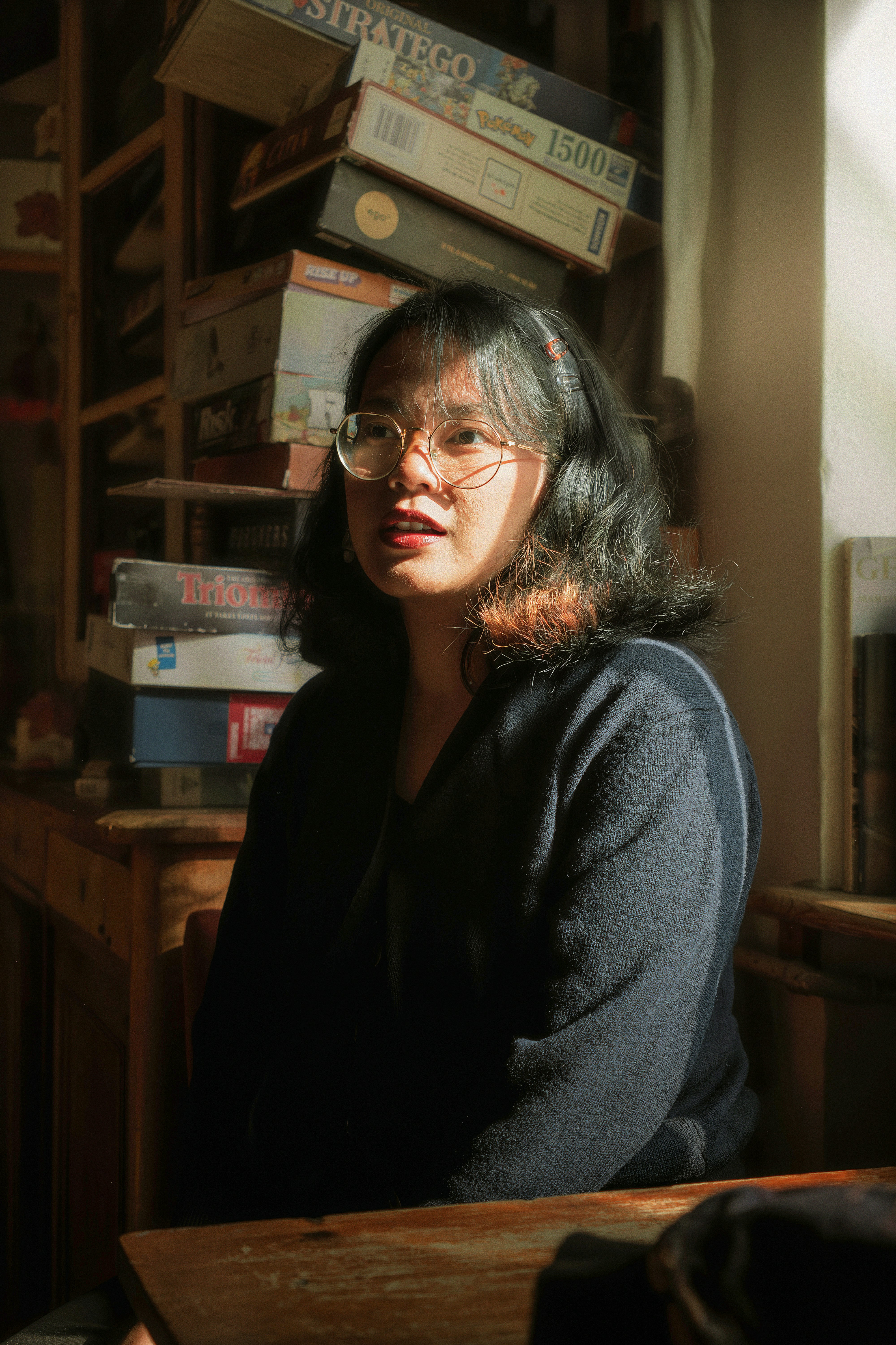 Woman with glasses in sunlight by board games
