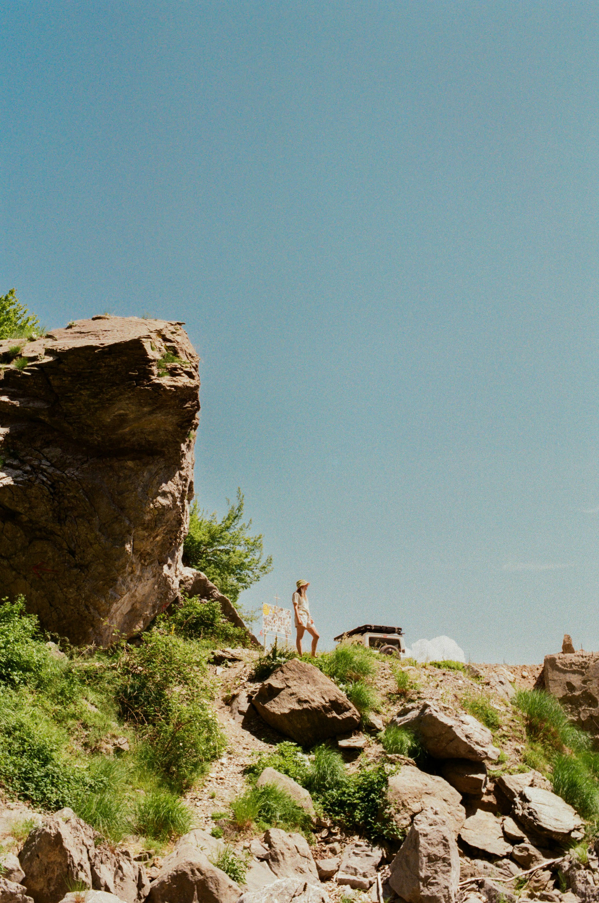 Woman on rocky cliffside under clear blue sky