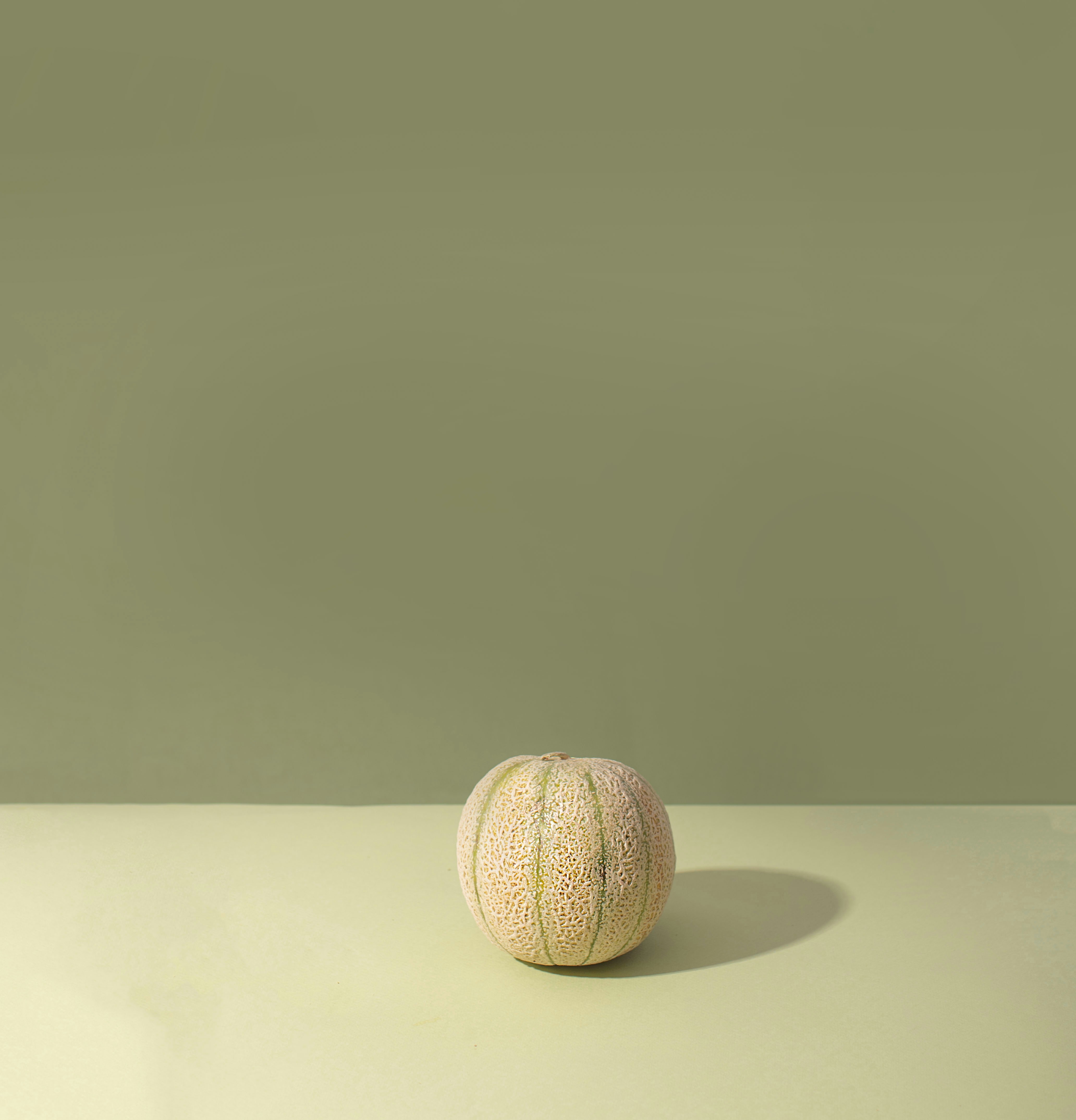 Small melon on a light green surface and background.
