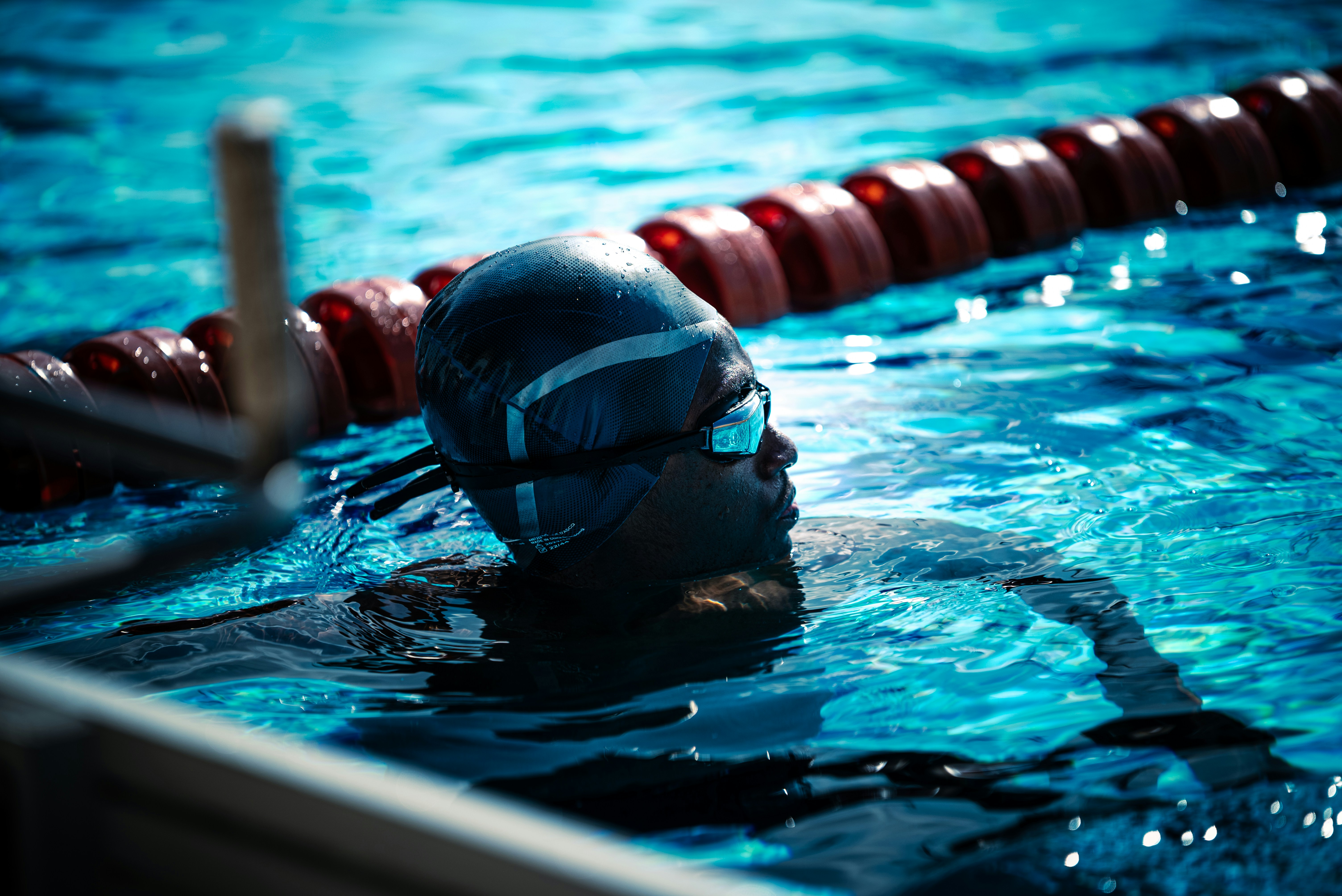 Schwimmer im blauen Pool mit Mütze und Schutzbrille