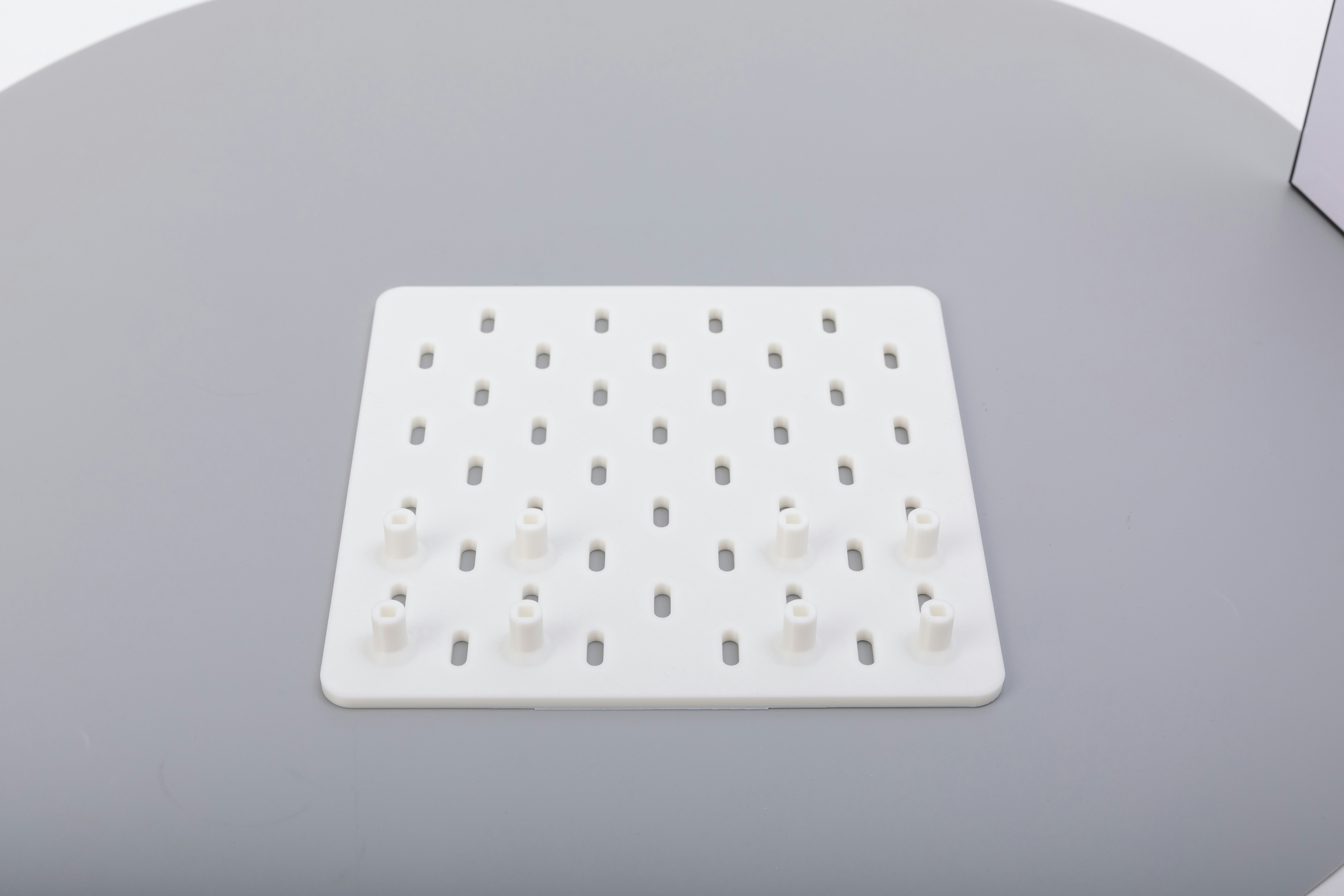 Ein weißes Pegboard mit einigen Stiften auf einer grauen Oberfläche.