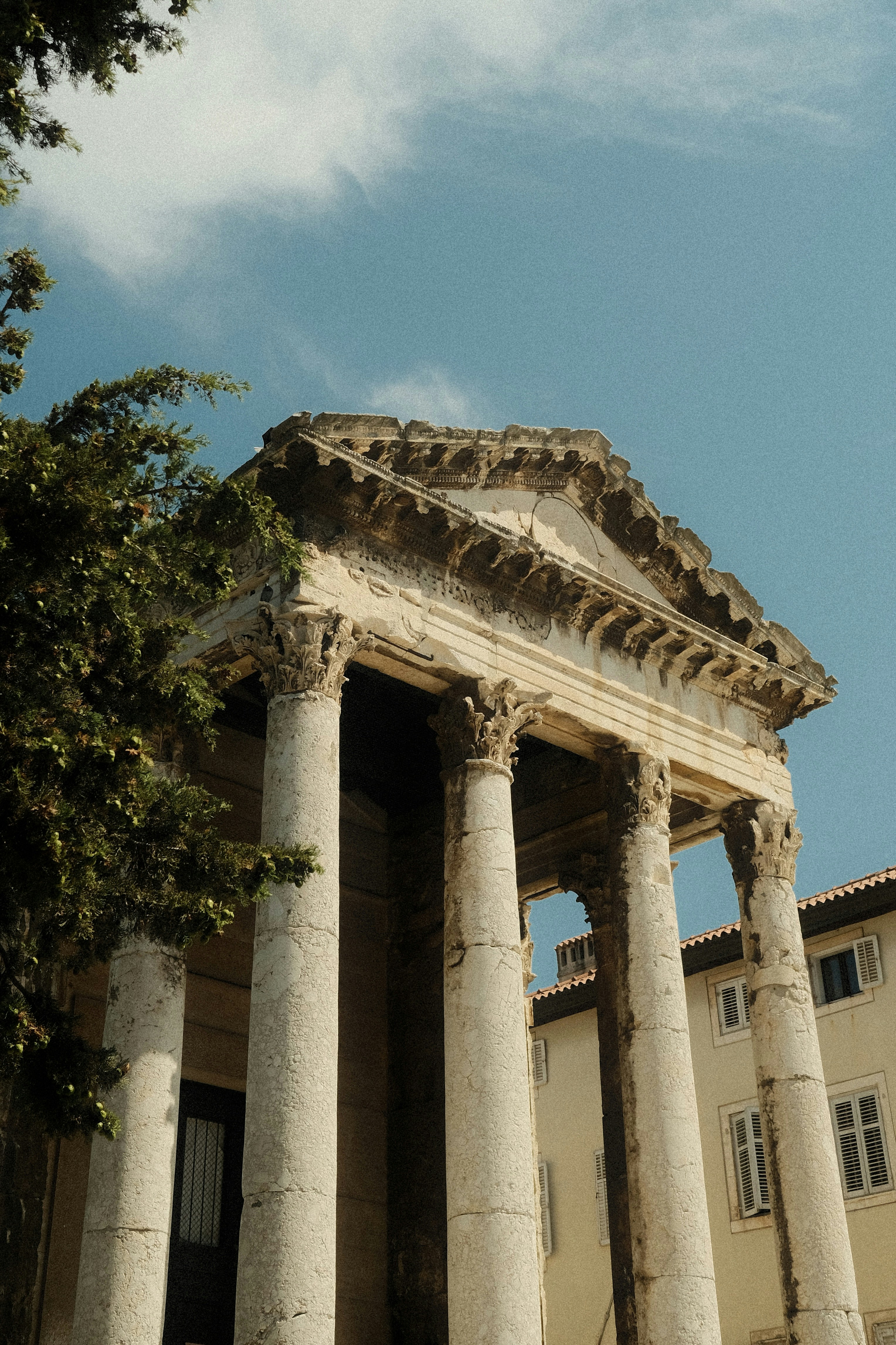 Ancient roman temple with classical columns against a blue sky.