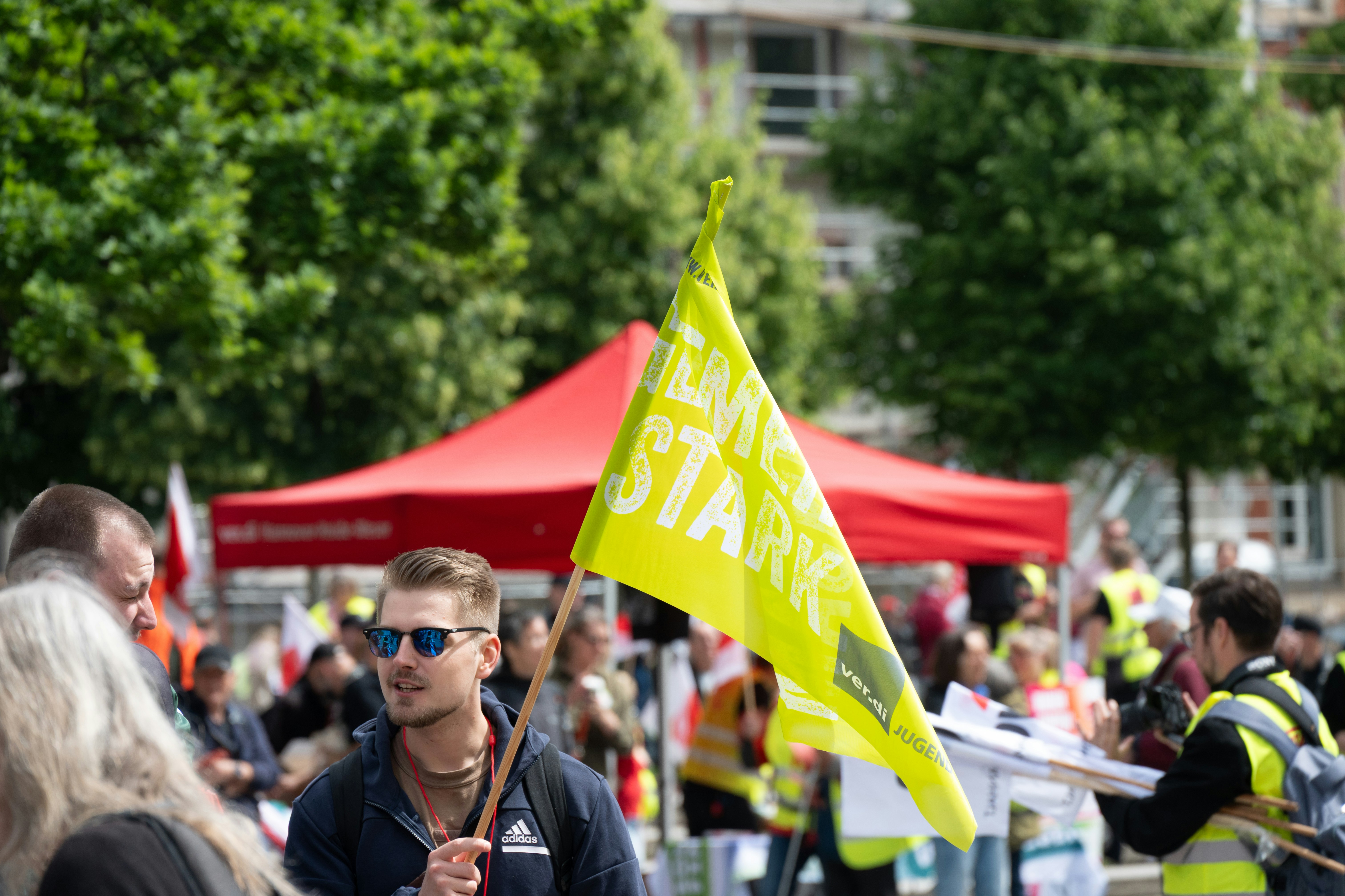 Mann hält eine gelbe Flagge bei einer überfüllten Outdoor-Veranstaltung.