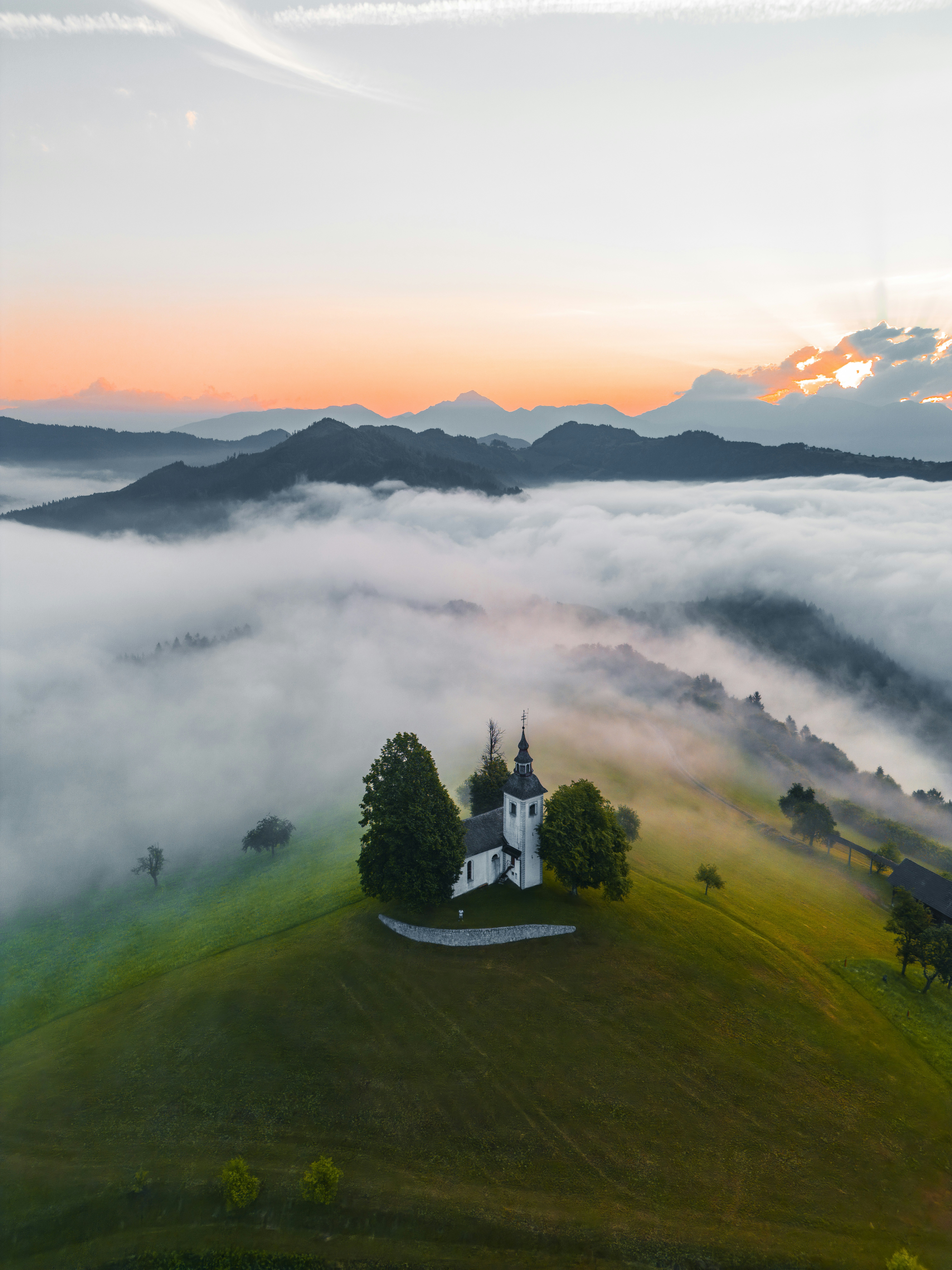 A church on a misty hill with mountains at sunrise