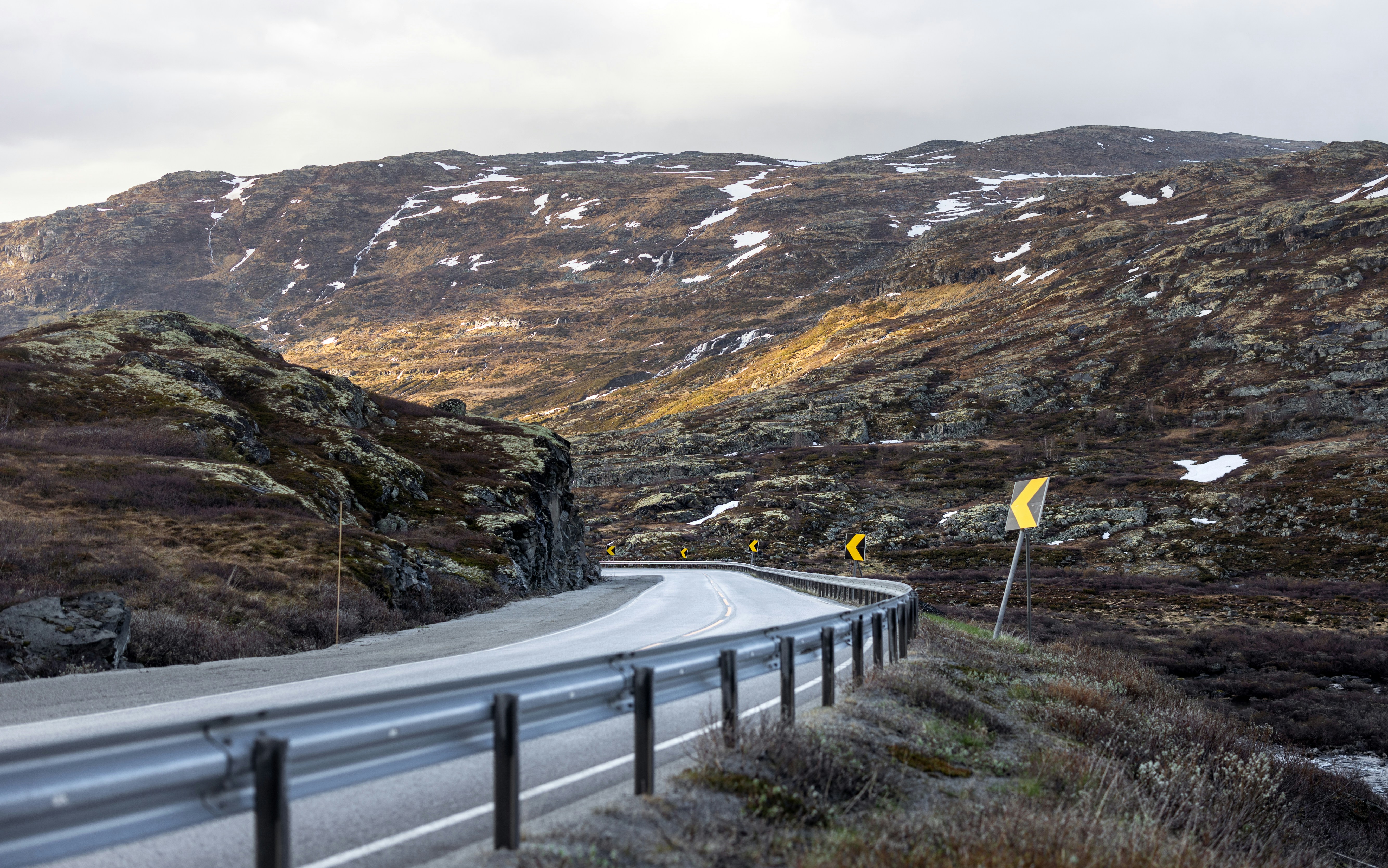 Svingete fjellvei gjennom snødekte fjell i Norge