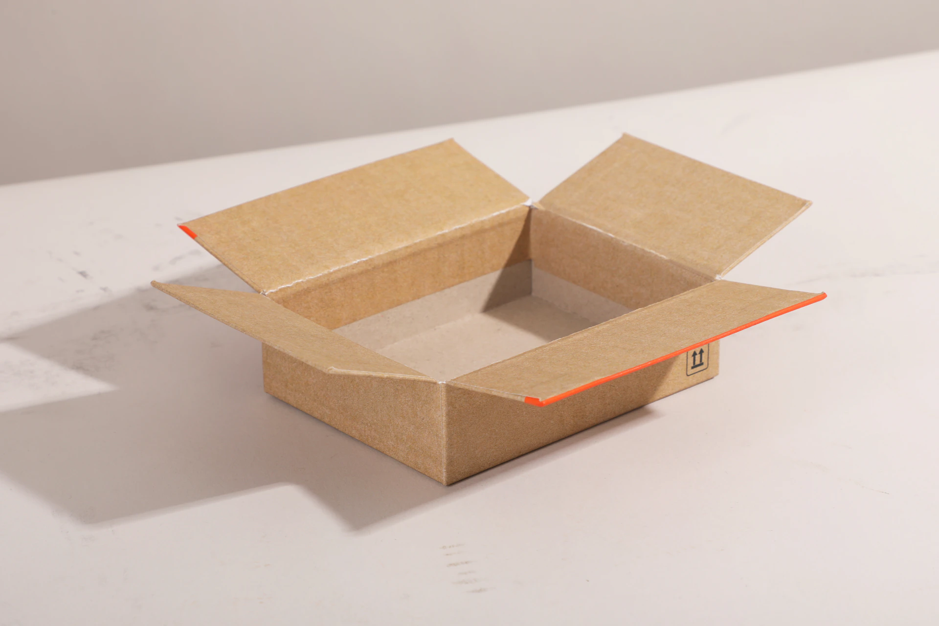 Open cardboard box with flaps on a light surface
