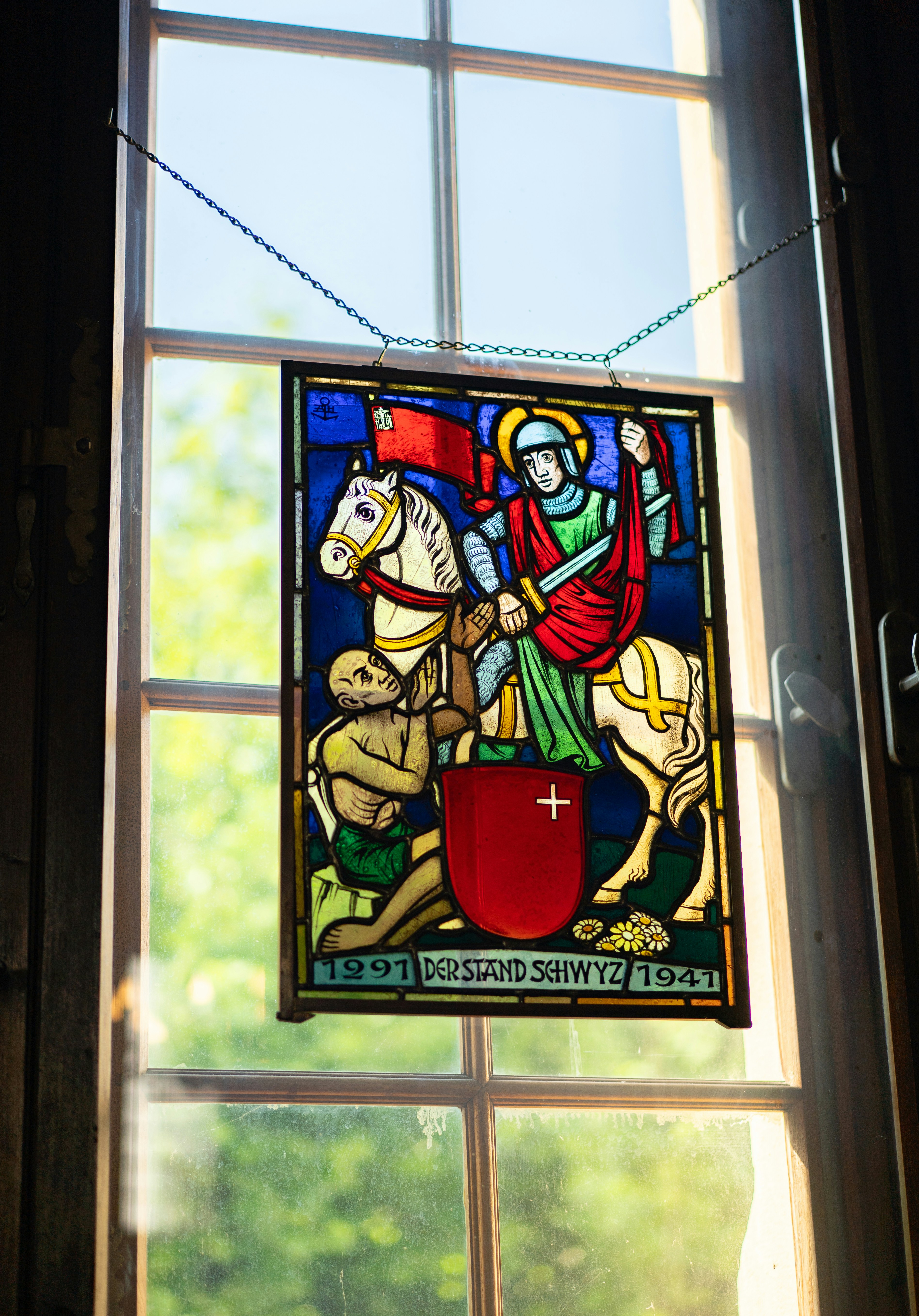Ornate stained glass panel with knight, horse, and swiss shield.