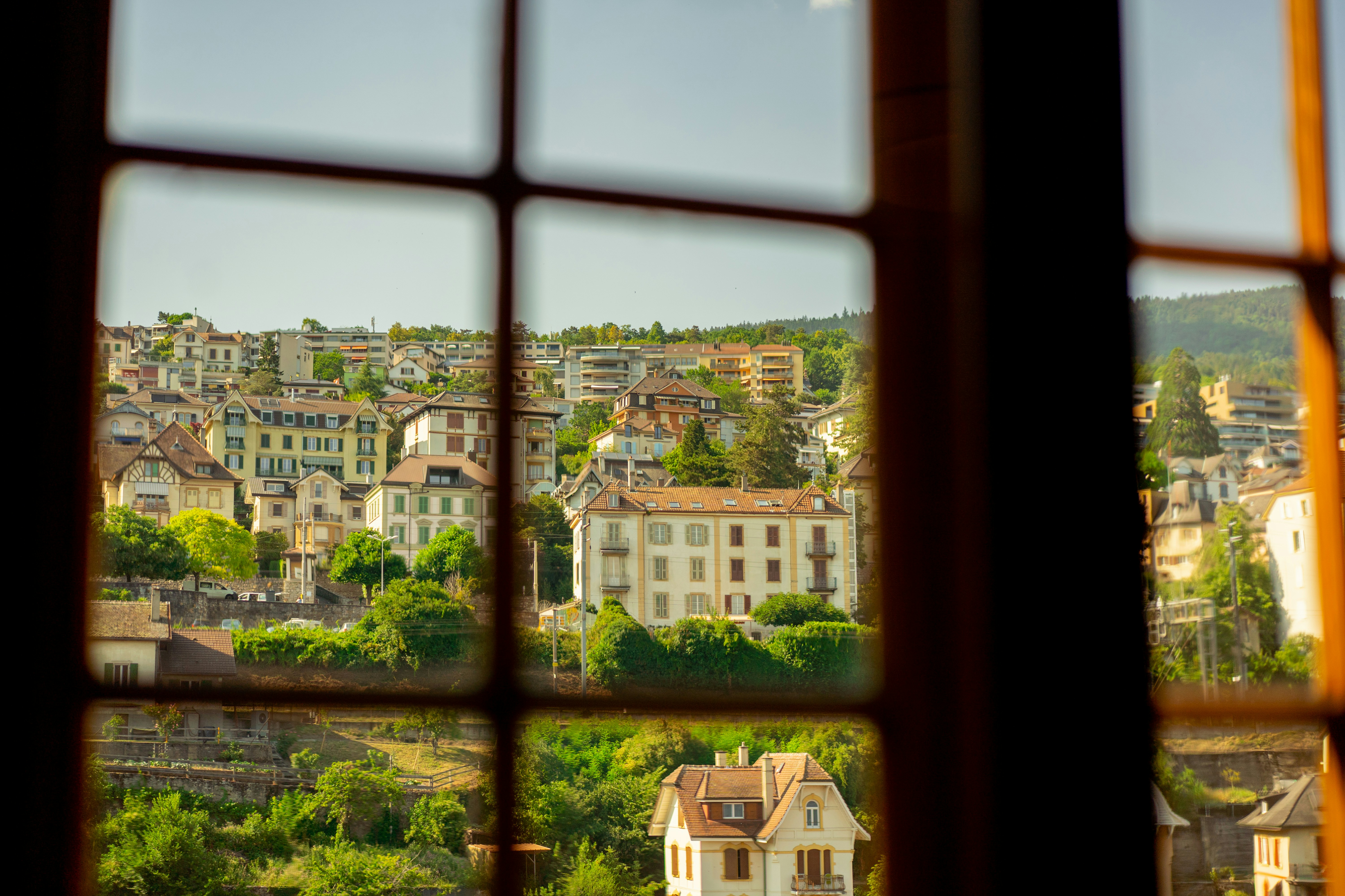 Historic town buildings and trees viewed through a window.