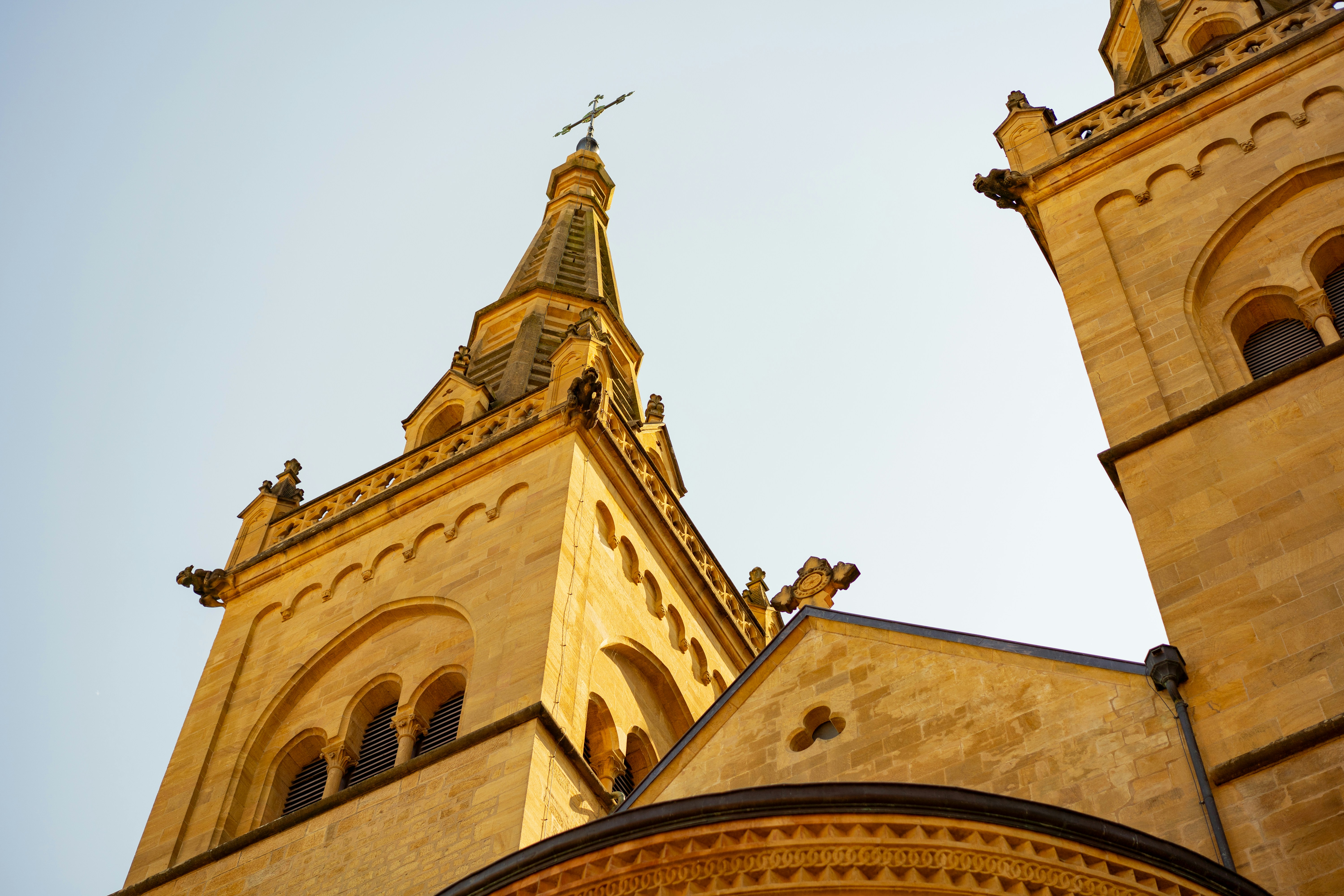 Ornate stone church towers and spire against a clear sky.
