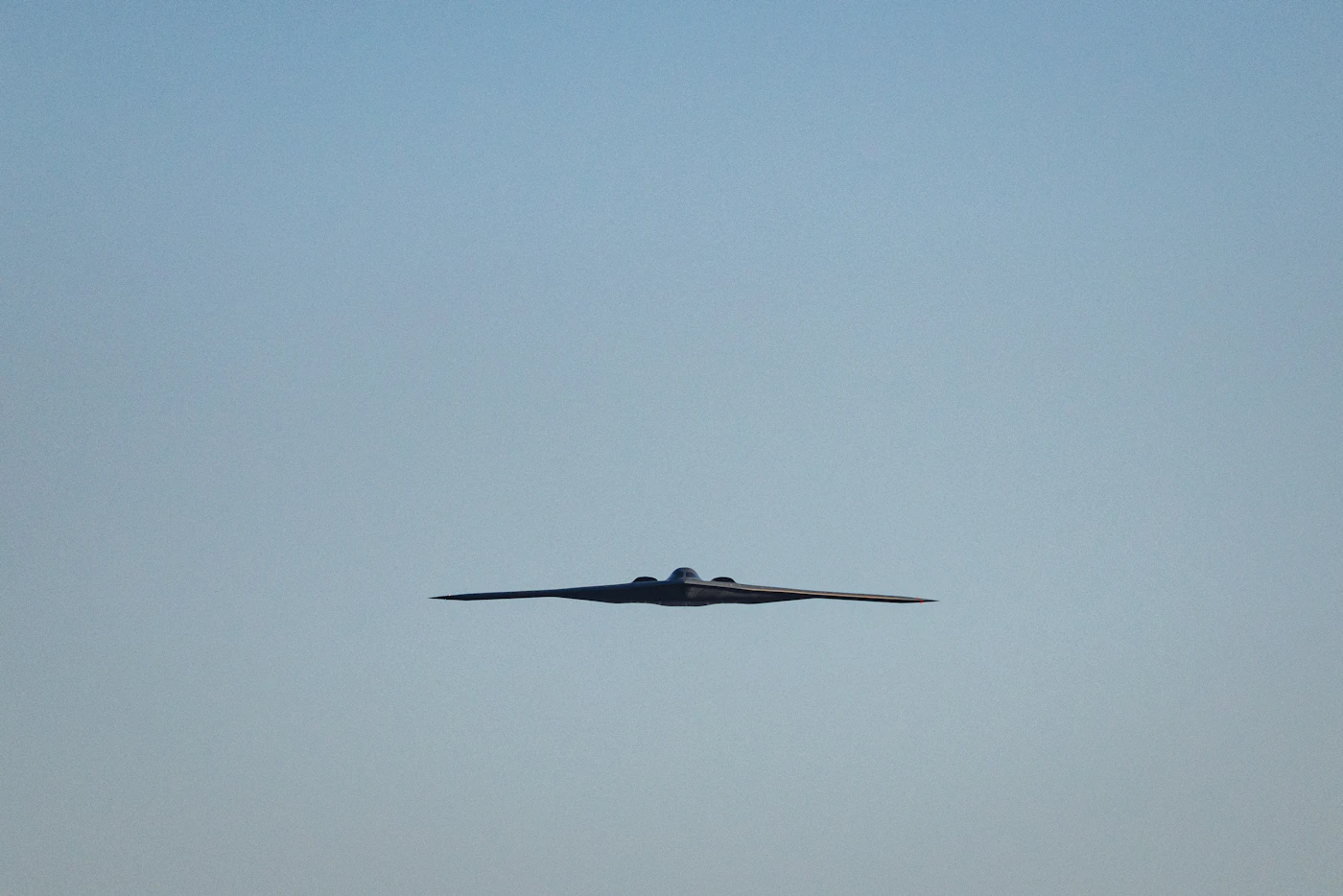 Bombardier furtif B-2 en vol, aile volante noire mate sur ciel clair, lors d'un survol du National Mall à Washington le 24 juin 2026