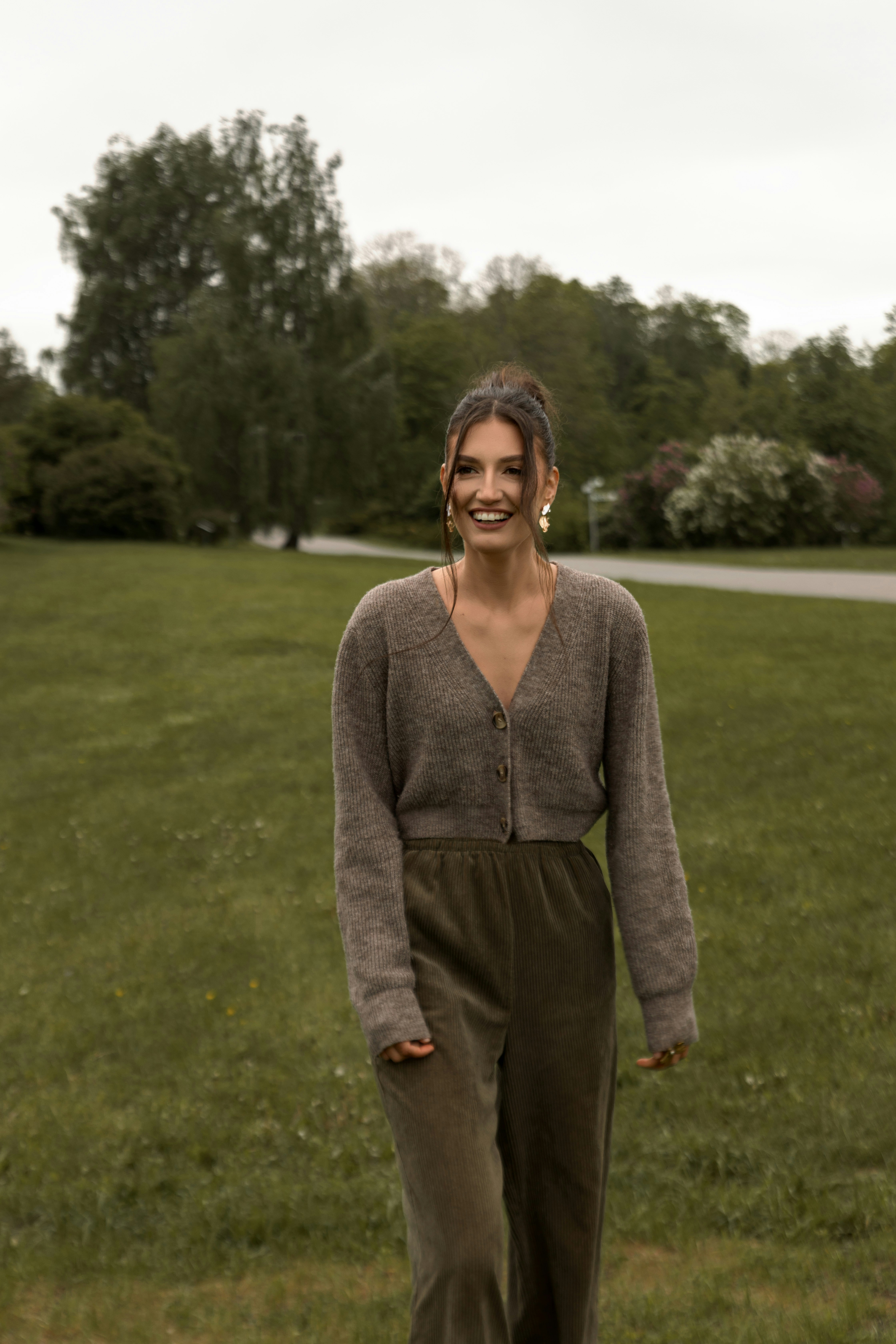 Uma mulher sorridente caminha em um parque verde.