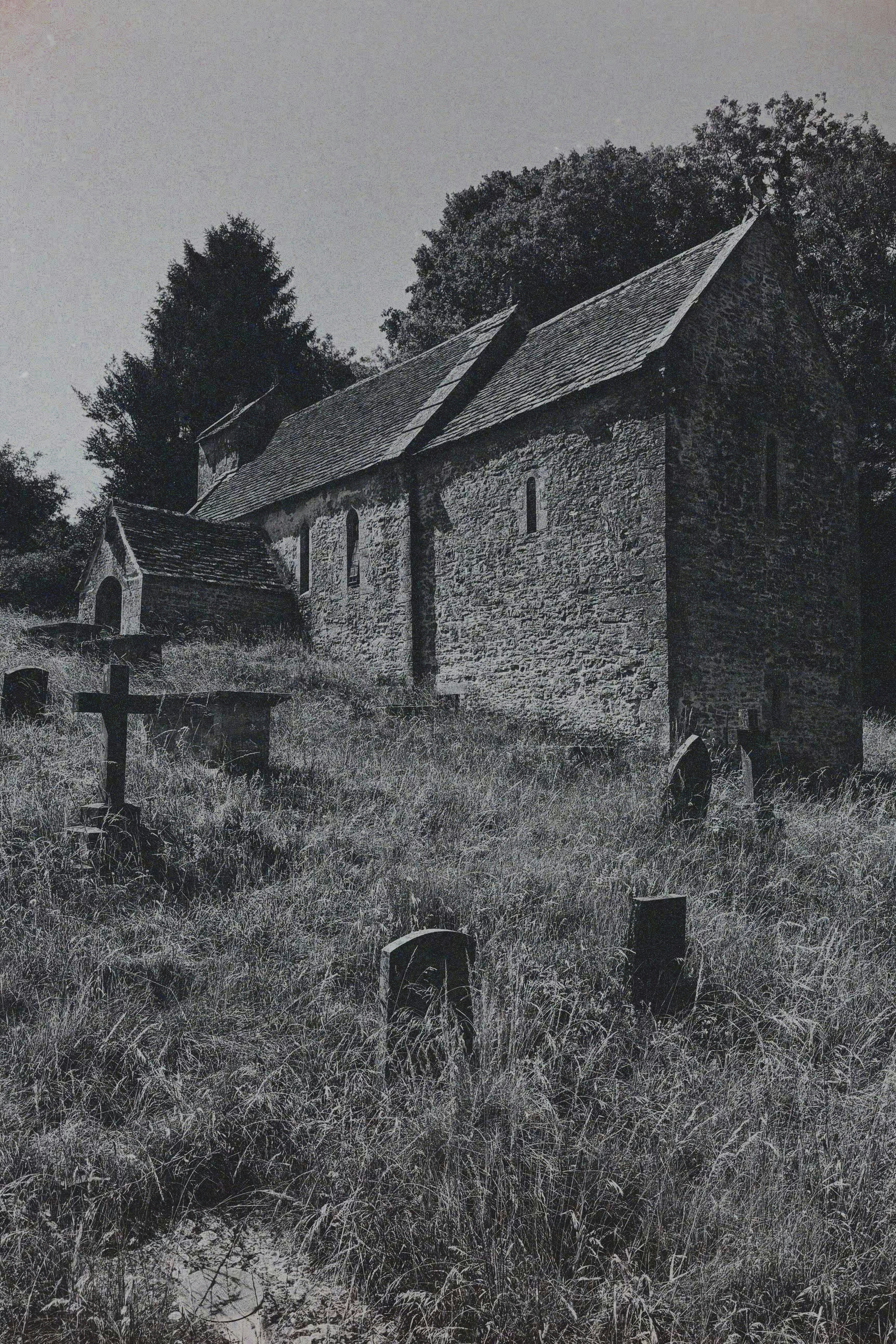 Gereja batu tua dengan kuburan dan rumput yang ditumbuhi.