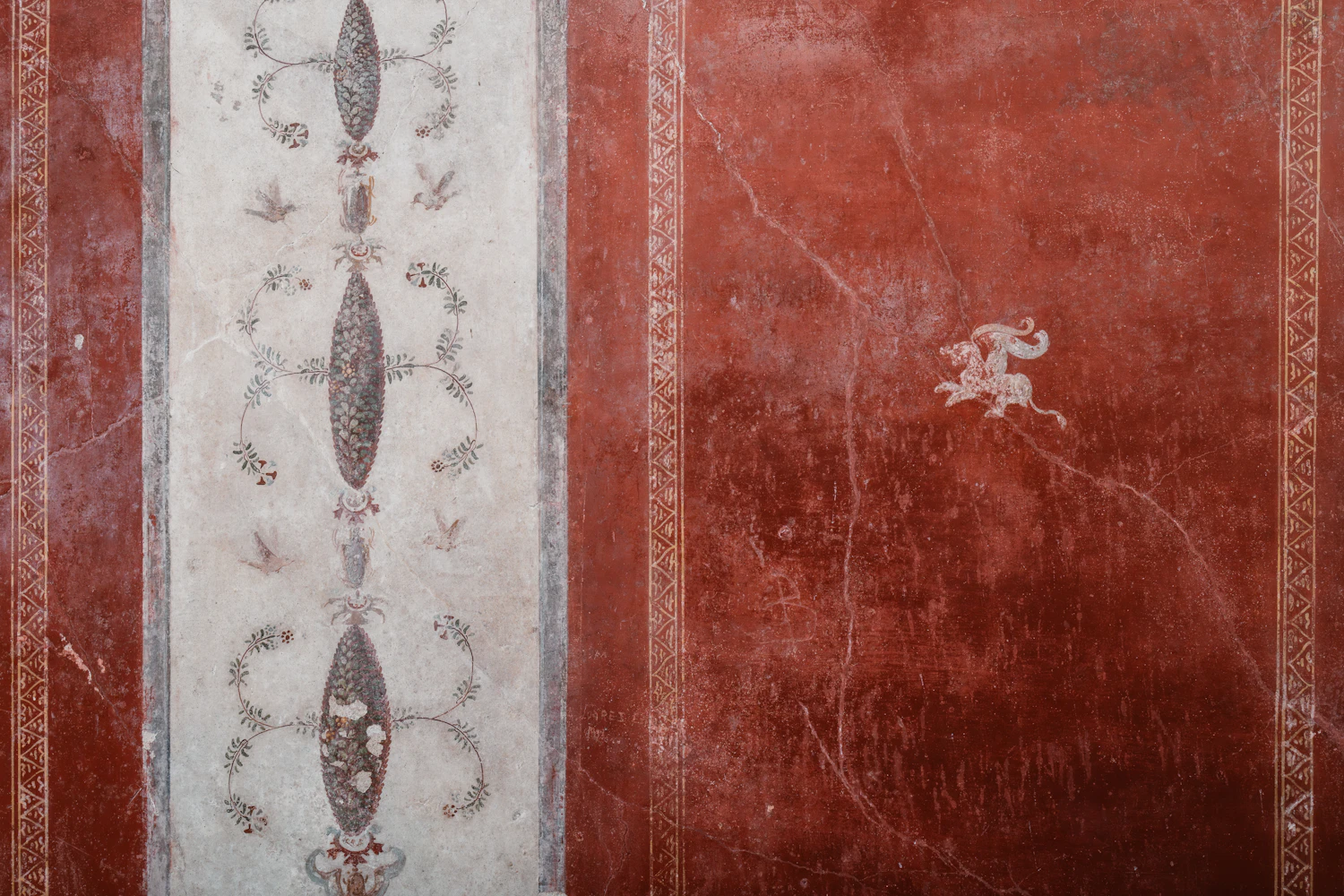 An ancient wall painting in deep red with a pale decorative panel at its centre