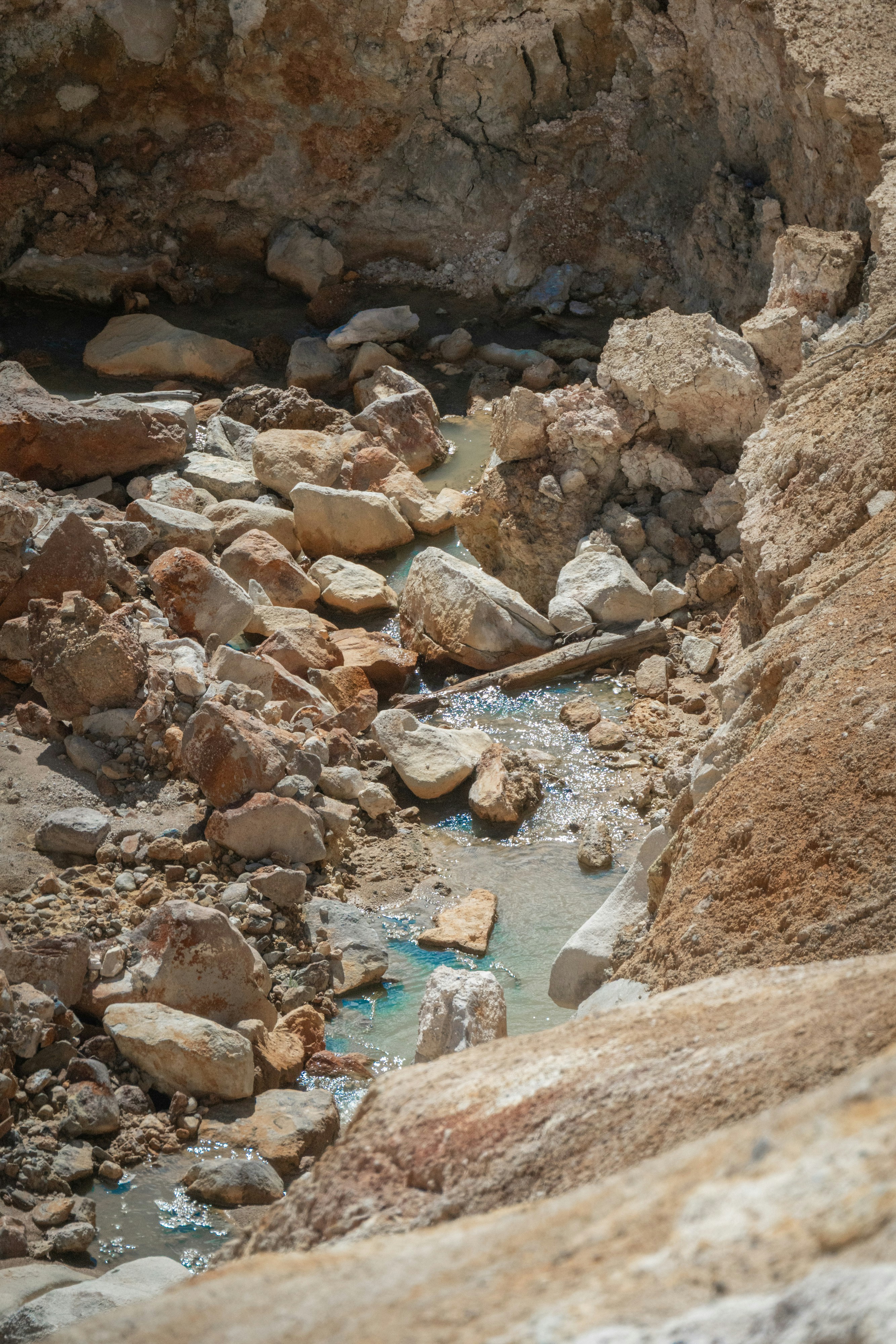 Rocky terrain with a small stream and colorful mineral deposits.
