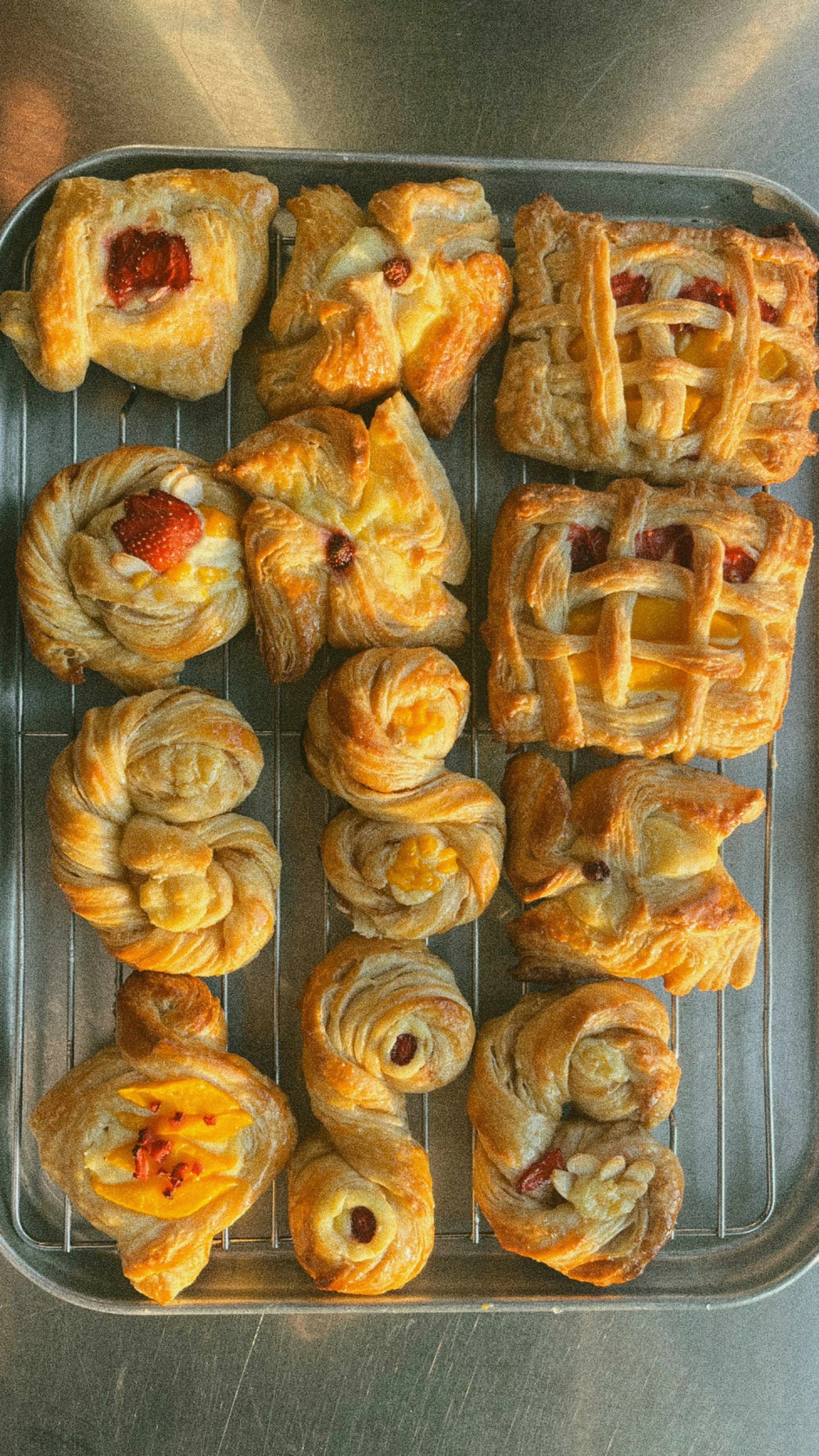 A tray of various fruit-filled pastries on a cooling rack