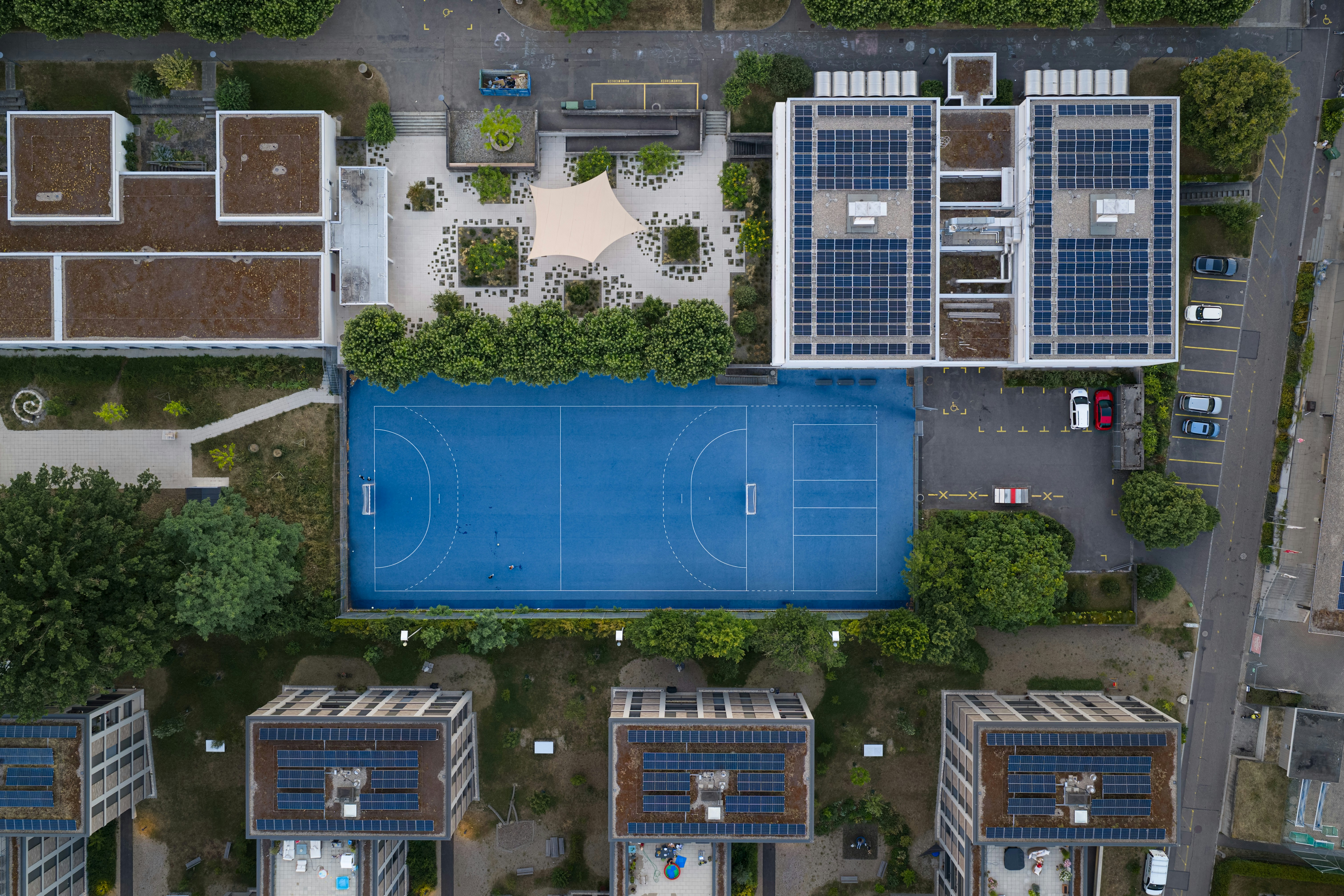 Blue sports court surrounded by buildings with solar panels