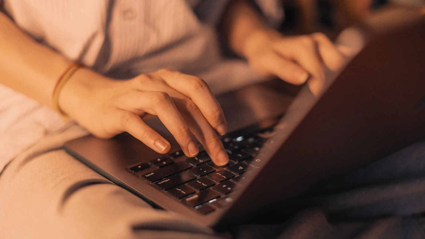 Hands working on a laptop at a desk.