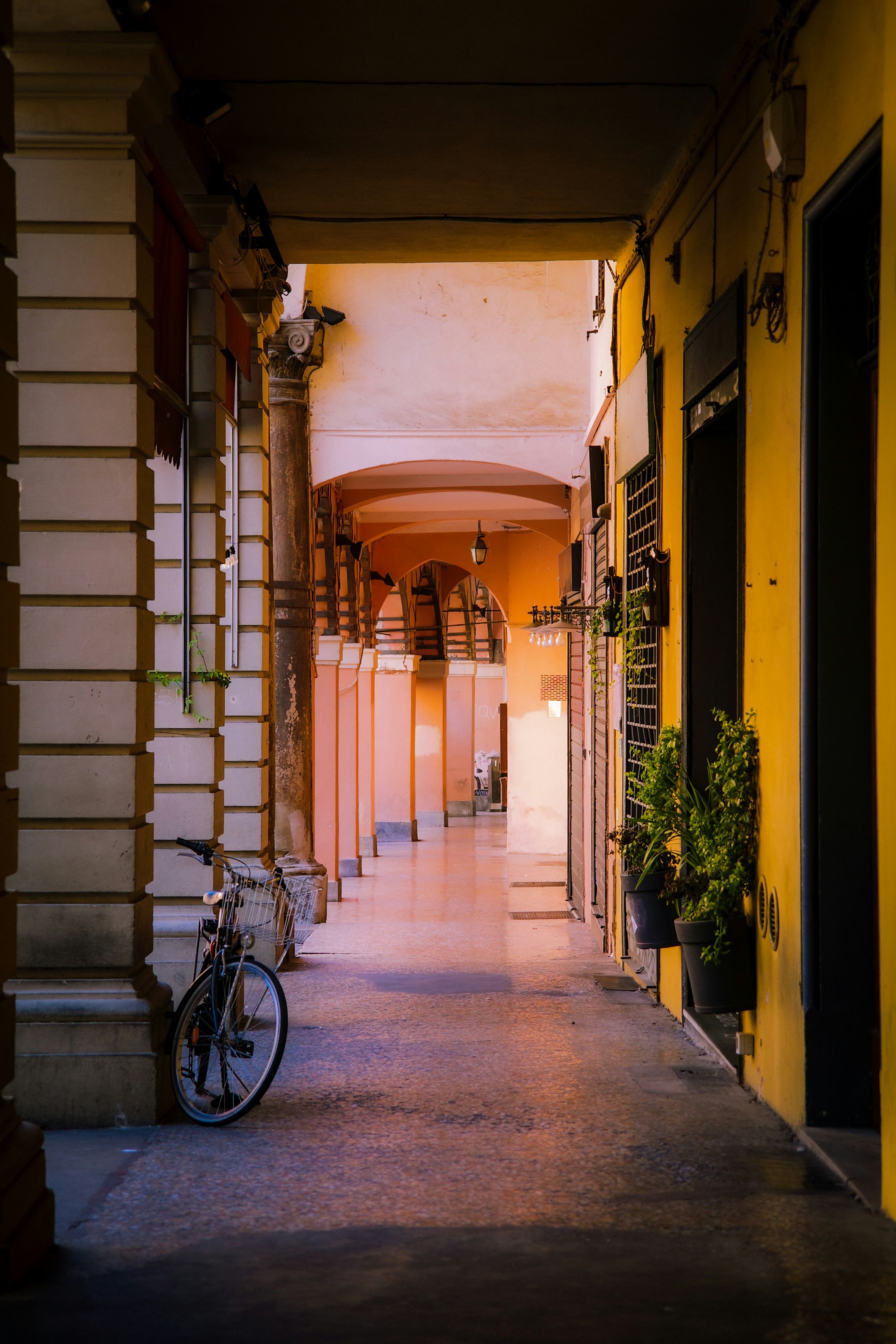 Arched walkway with a bicycle and vibrant yellow wall