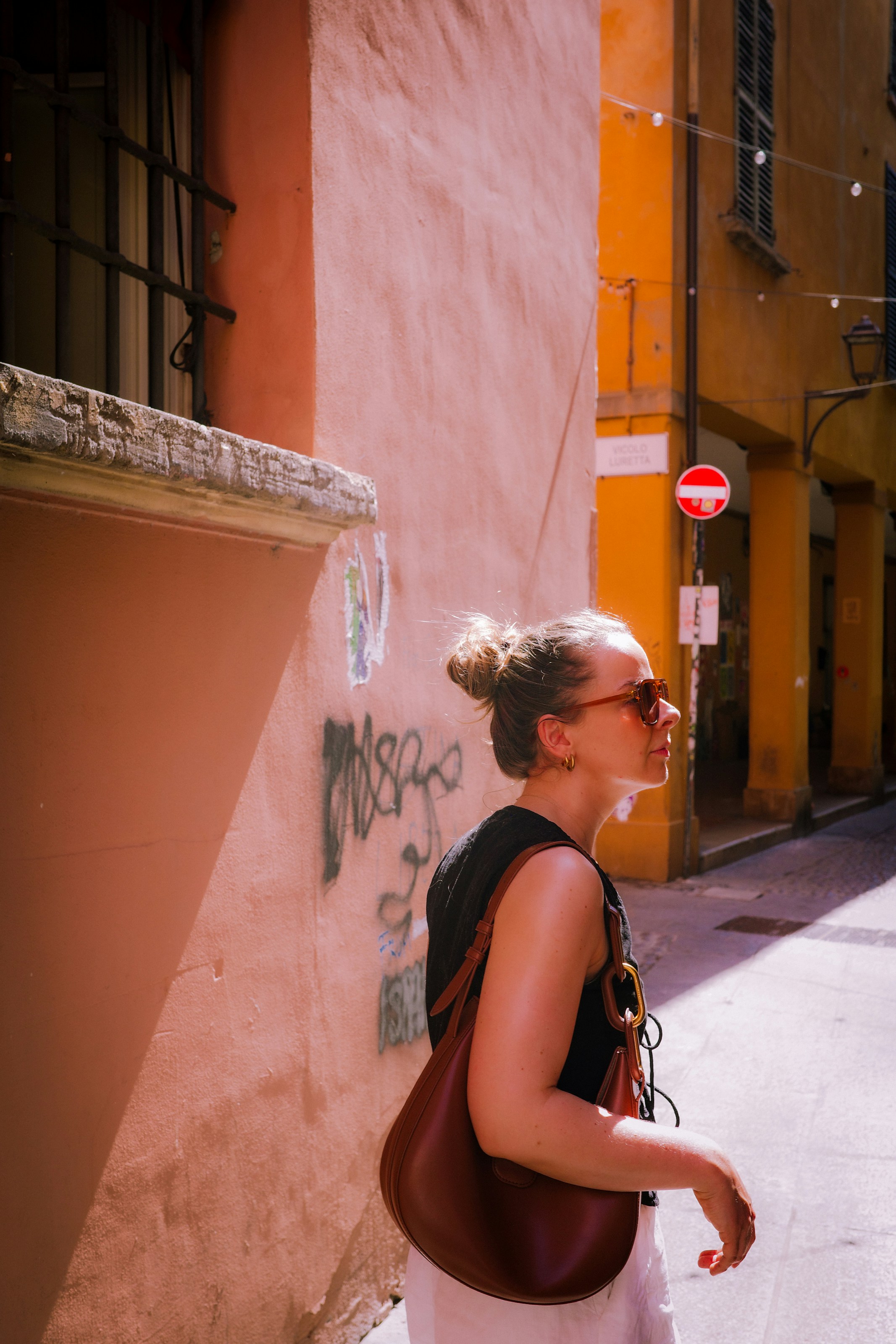 Woman with bun and sunglasses on a sunlit street