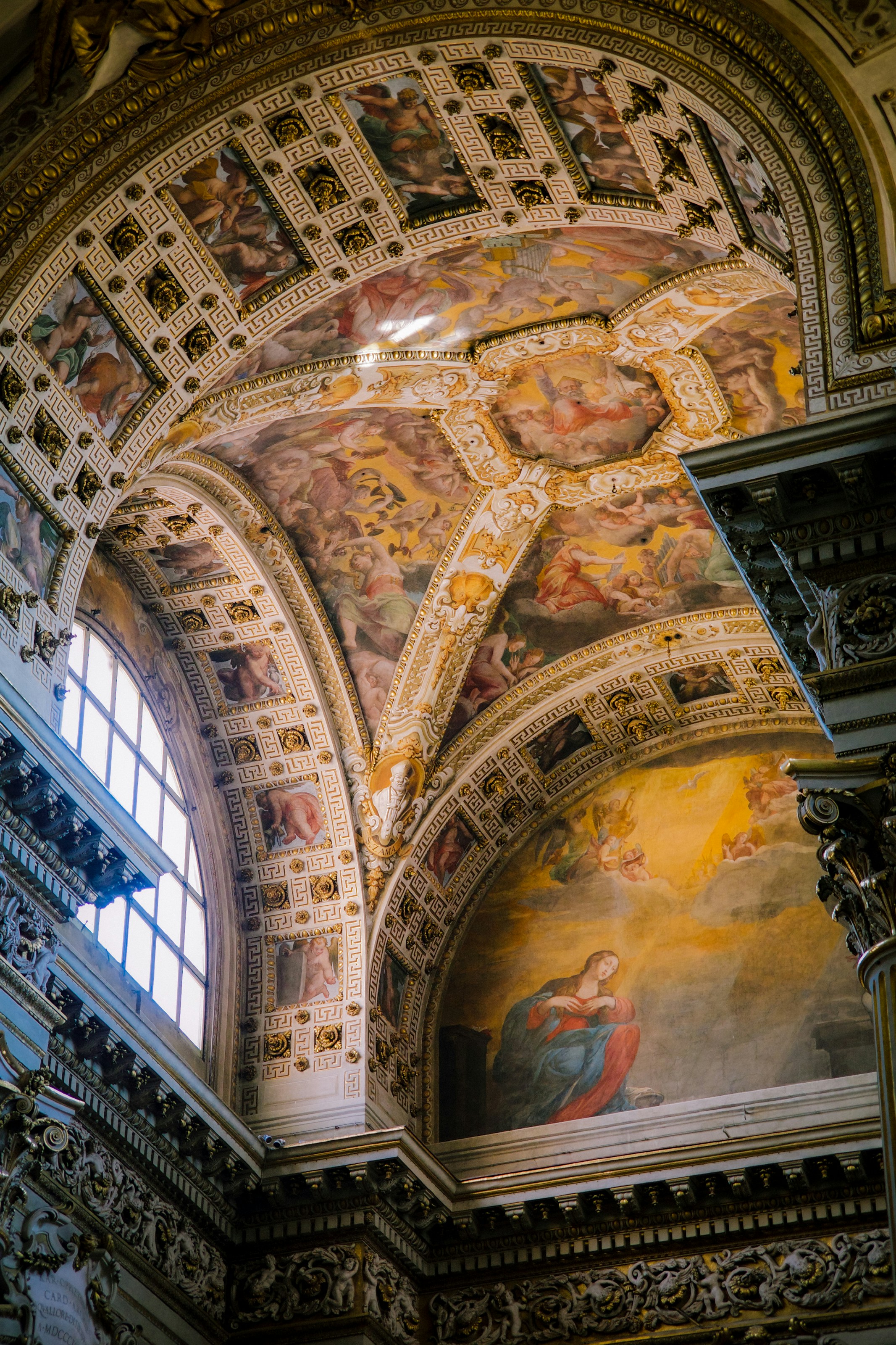 Ornate church ceiling with frescoes, arches, and a bright window