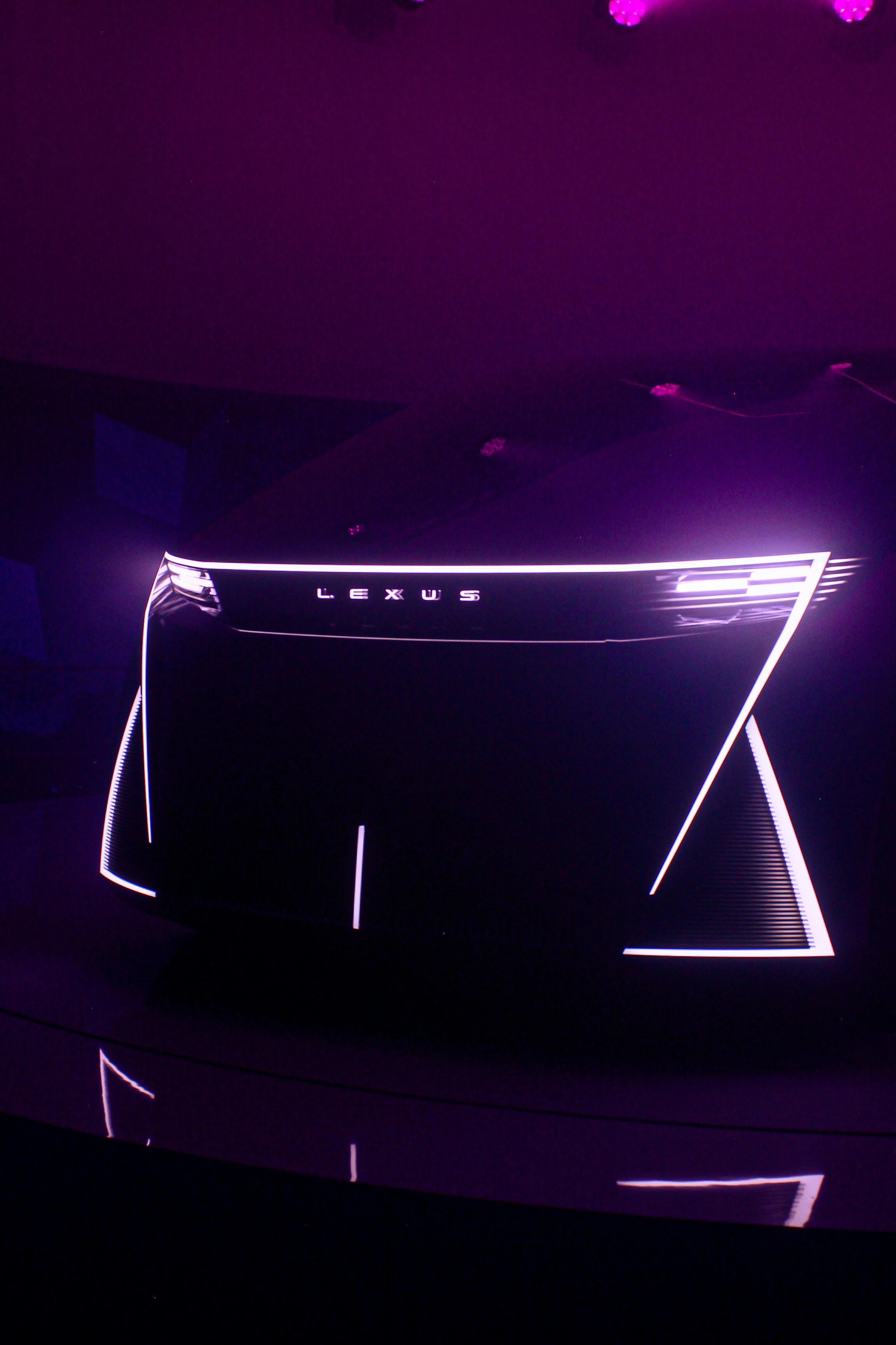 Illuminated lexus logo with futuristic light design on dark background.