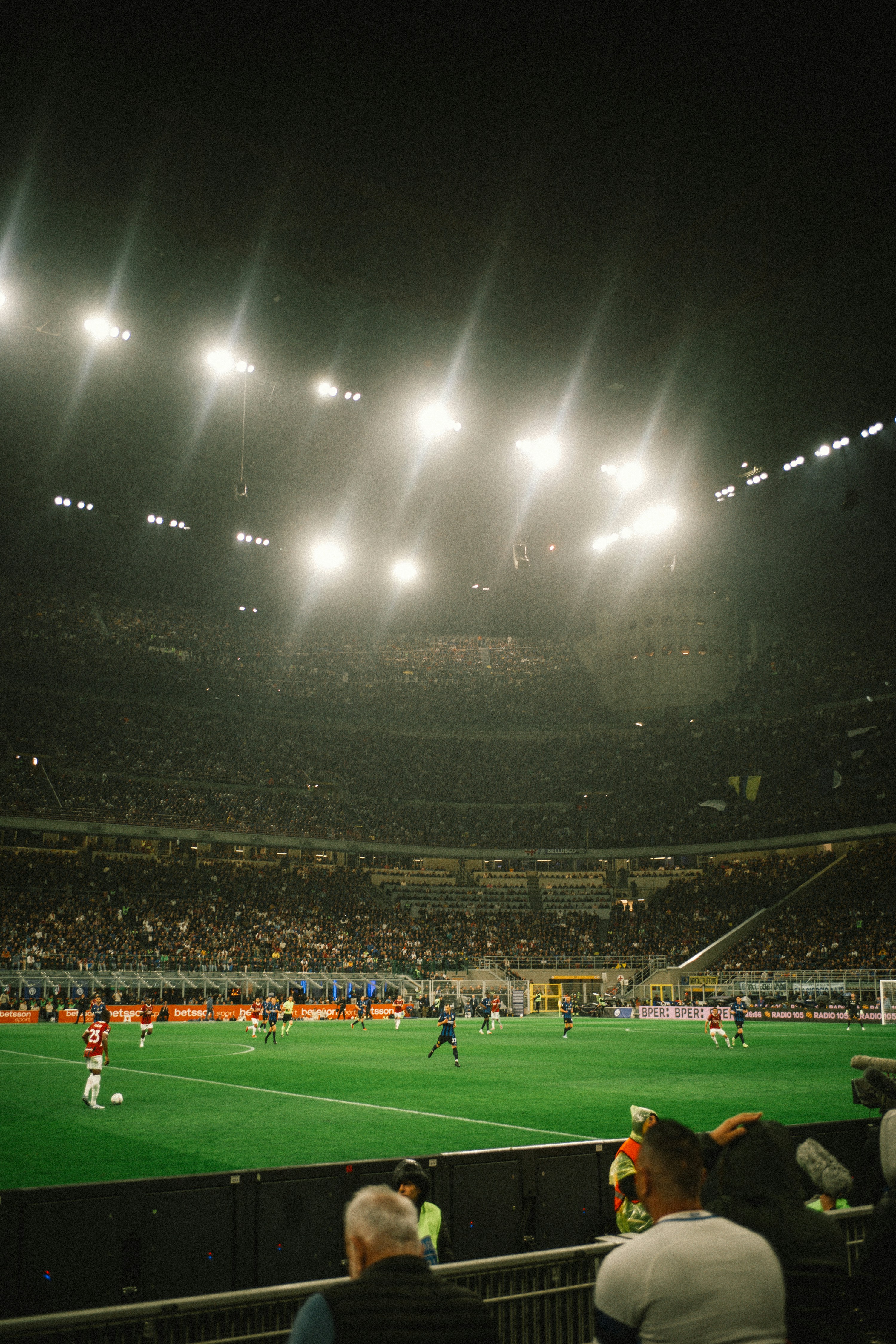 Football match at night in a crowded, brightly lit stadium