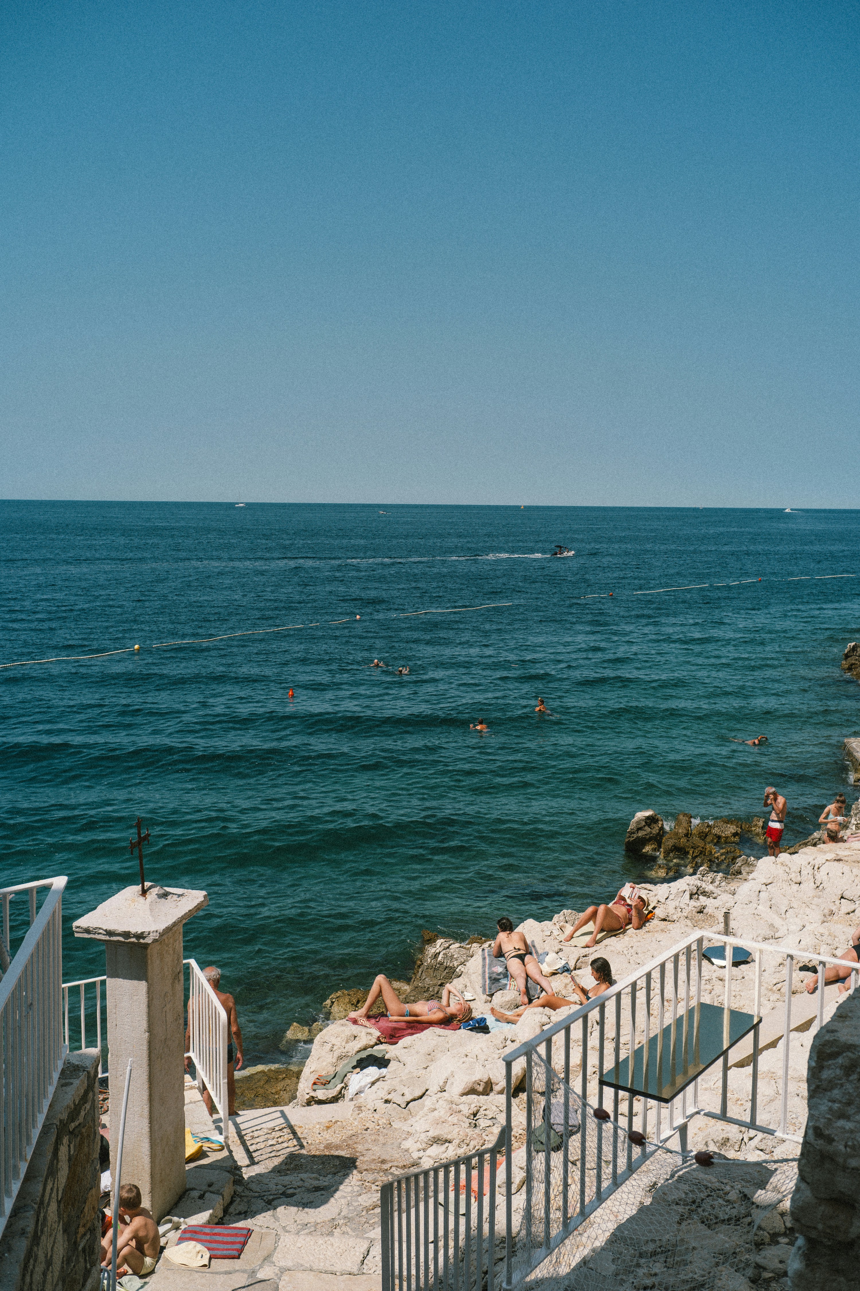 People swimming and sunbathing on a rocky coastline
